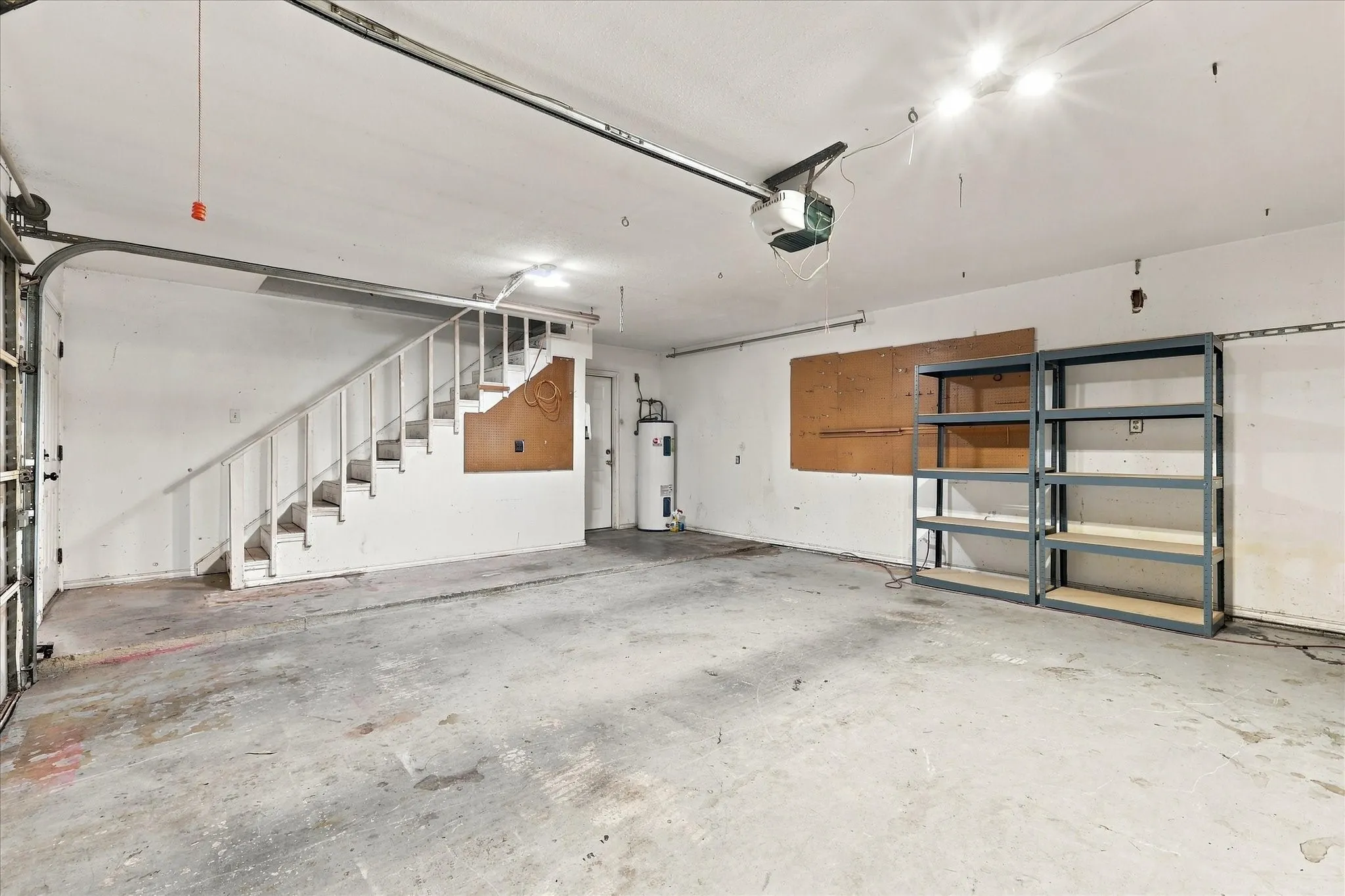 Garage space featuring a concrete floor, stairway access, and built-in shelving