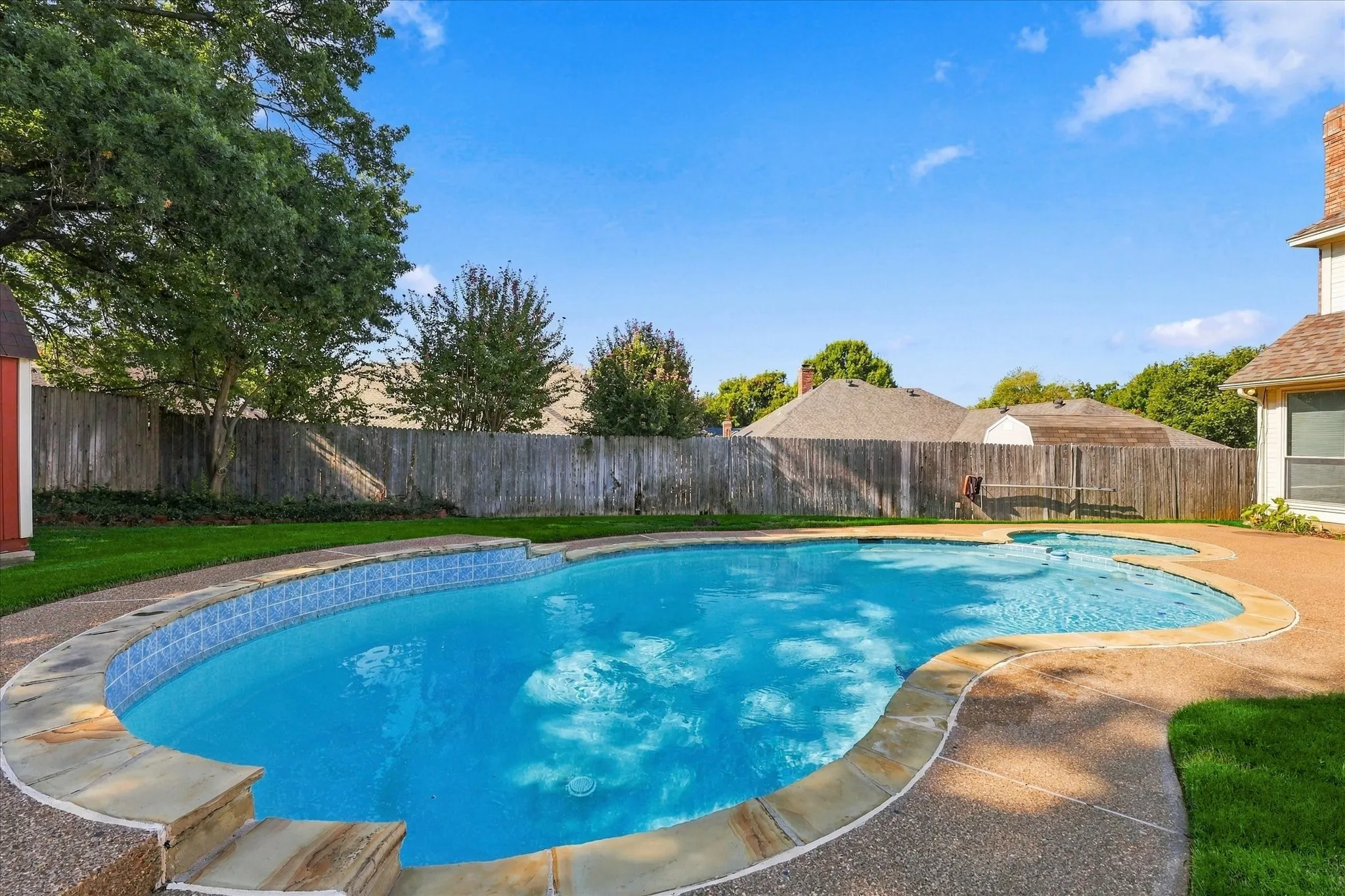 Freeform swimming pool with a stone coping and a light blue tile-line