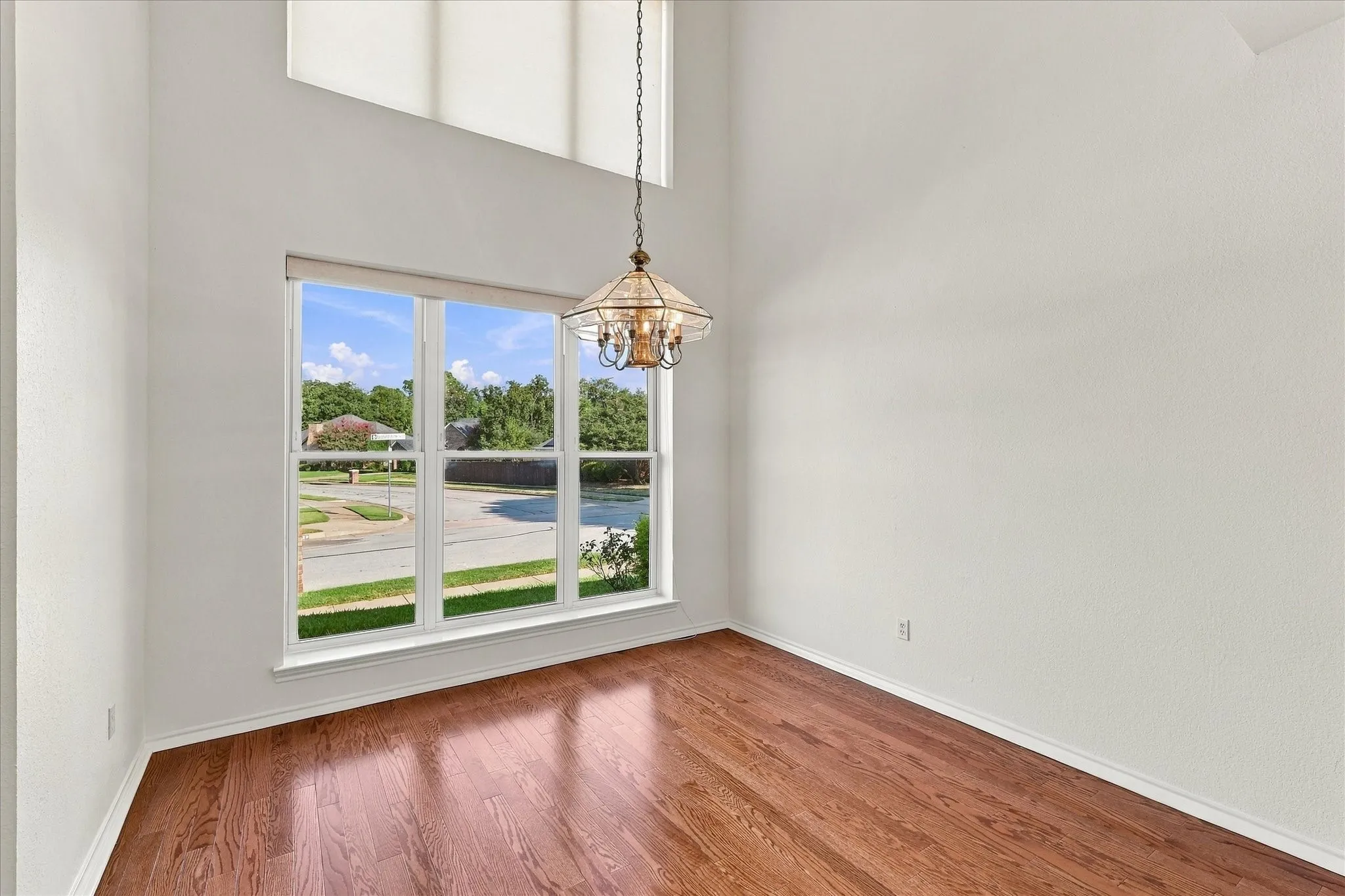Hardwood flooring, high vaulted ceiling, large picture windows, and a classic chandelier