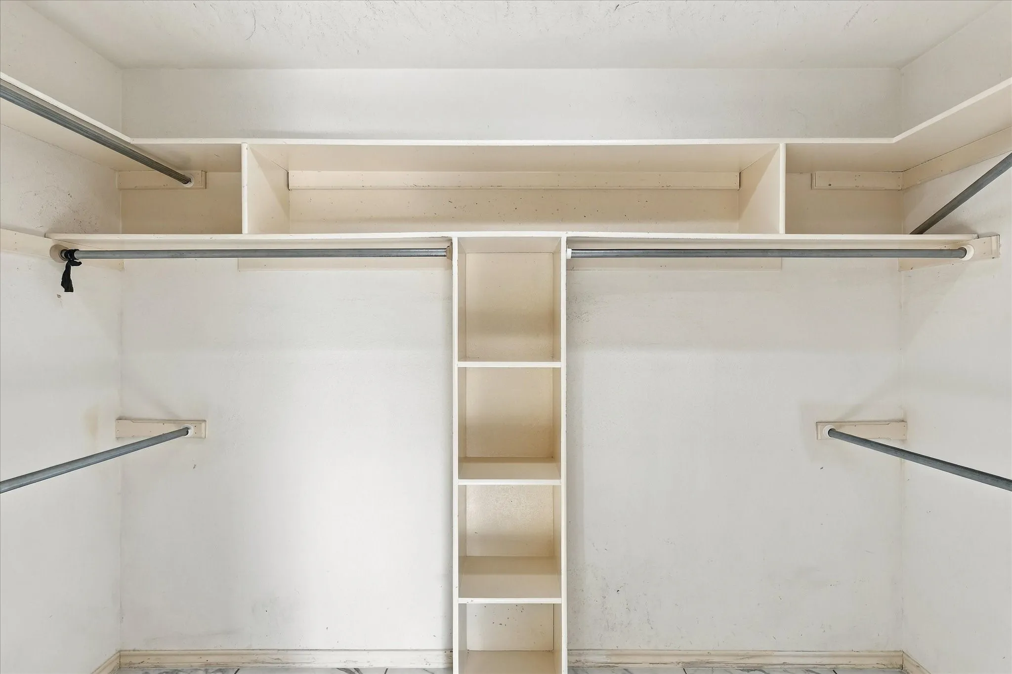 Built-in closet organization system featuring shelving and multiple hanging rods