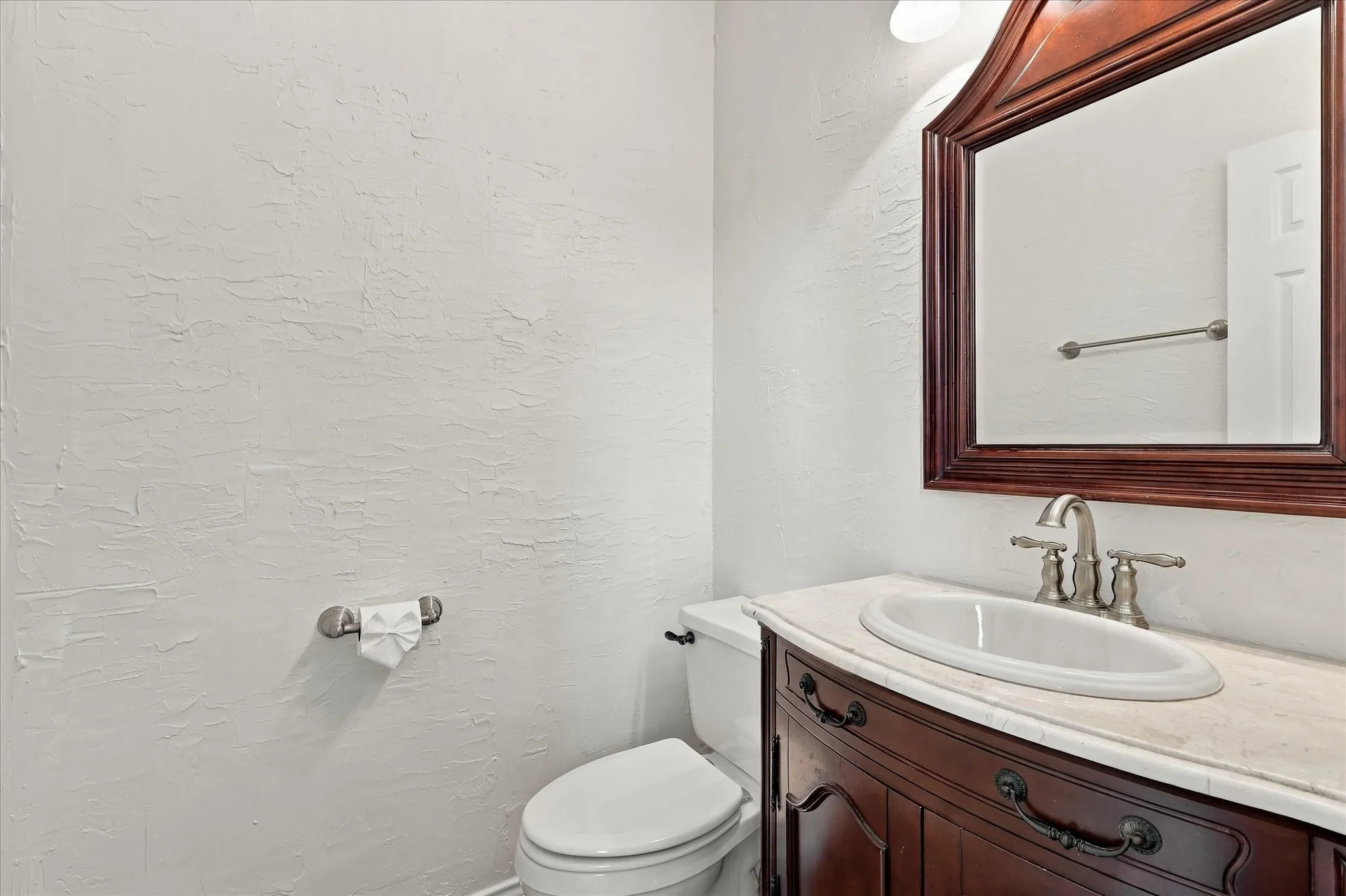 Powder room off of living room foyer Recessed vanity with a light-toned countertop, oval undermount sink, and brushed nickel faucet