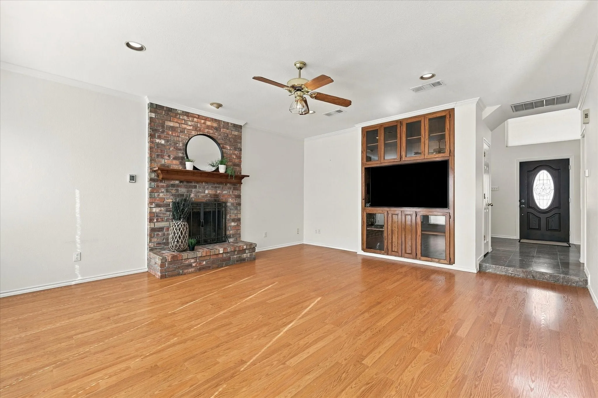 Brick fireplace with wood mantel, built-in entertainment center, wood-finish flooring, recessed lighting, and ceiling fan