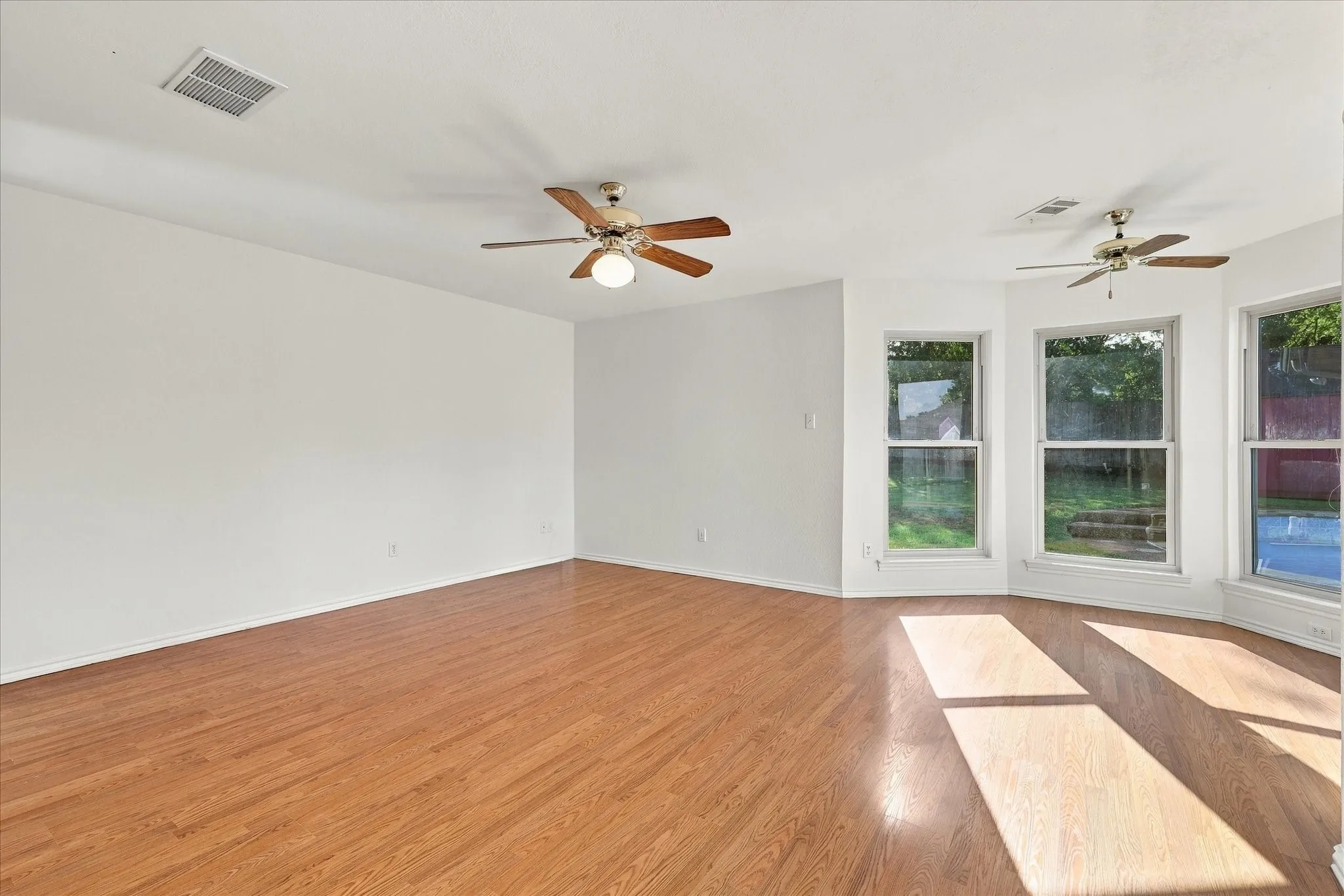 Wood-finish flooring throughout, multiple ceiling fans, and a bay window configuration
