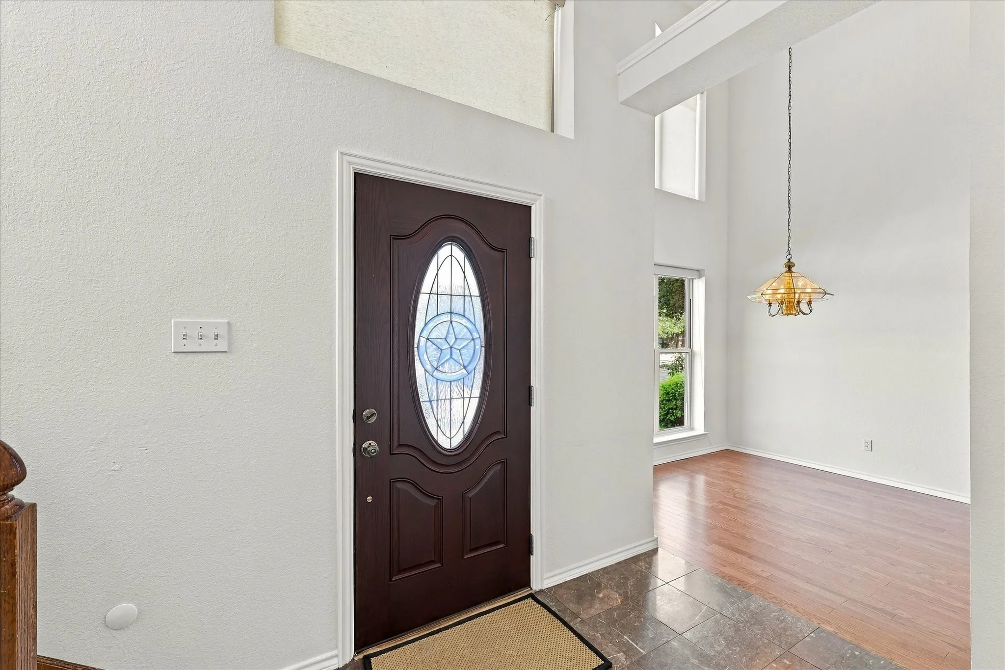 Entryway featuring a dark finish door with decorative glass, a two-story ceiling, multiple windows, and a hanging light fixture