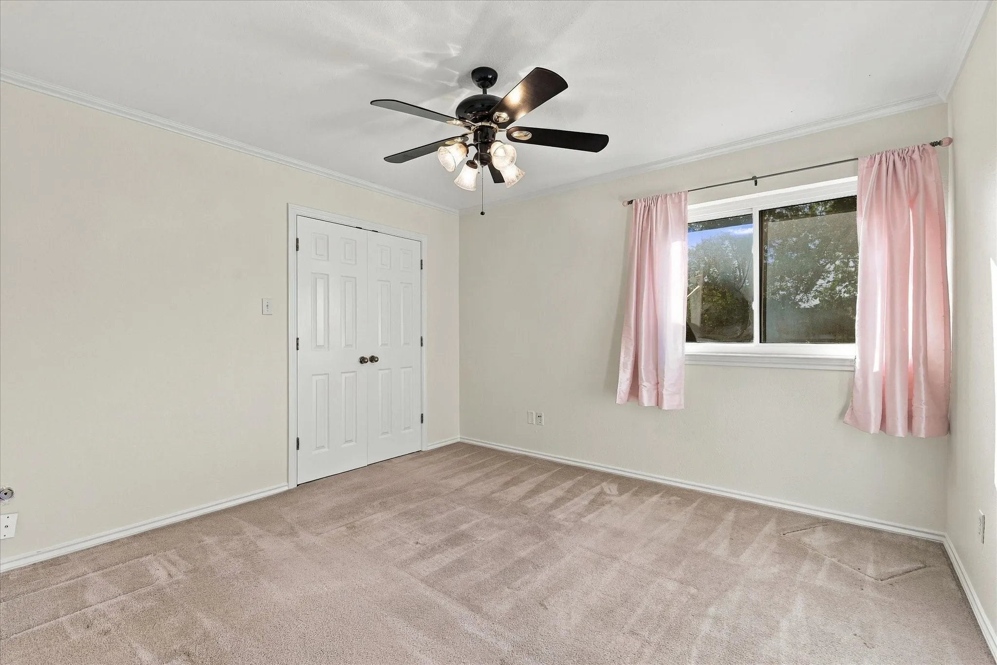 Looking into bedroom Carpeted flooring, white trim, ceiling fan with integrated lighting, and a double-door closet
