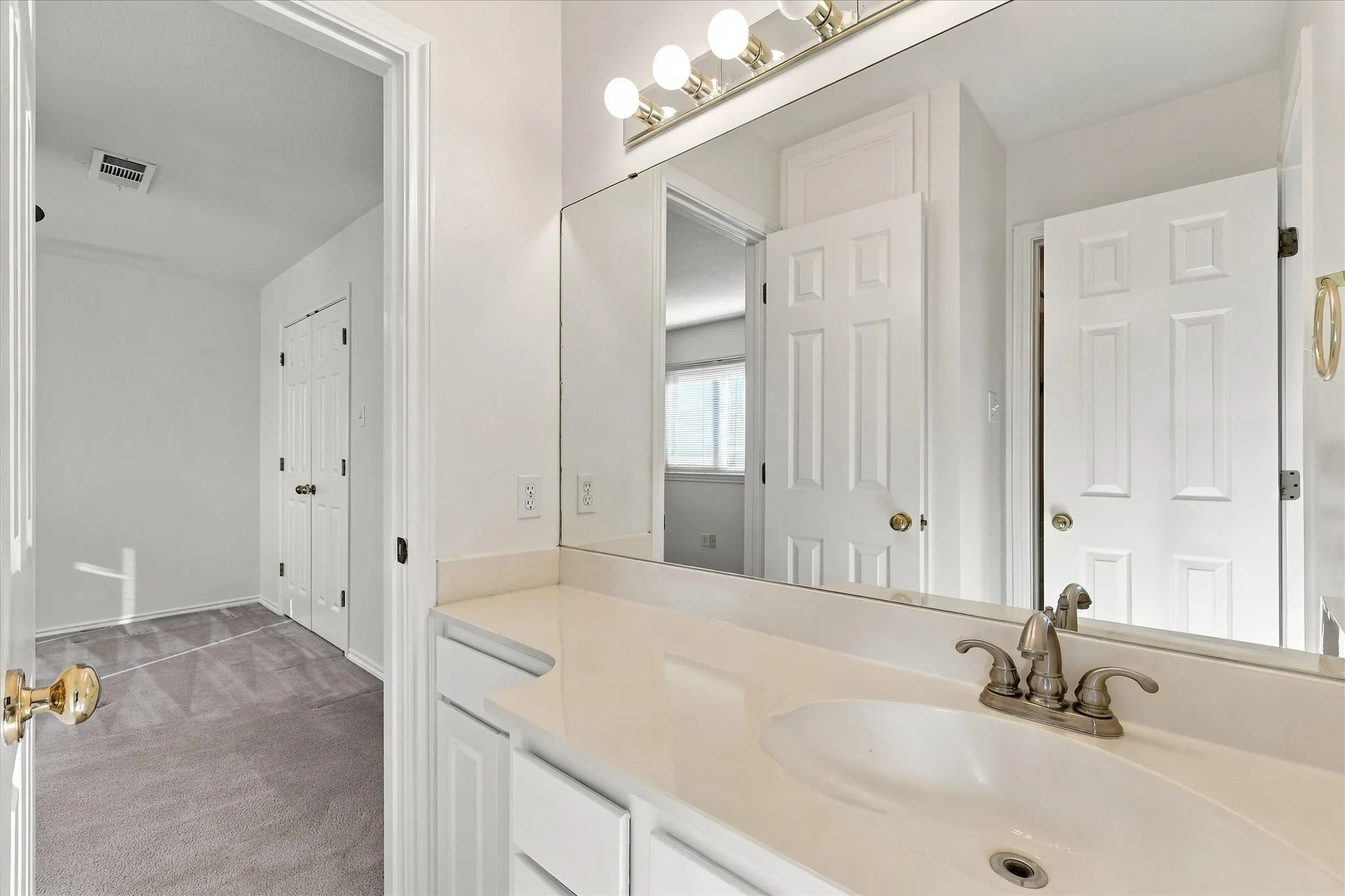 Jack and Jill bath upstairs White vanity with integrated sink, brushed nickel faucet, large mirror, and overhead vanity lighting