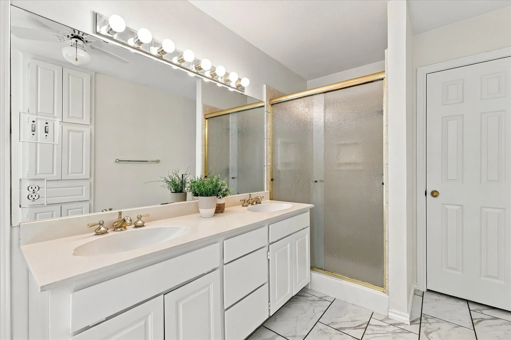 Dual vanity with undermount sinks, stone-finish countertop, and brass-tone fixtures