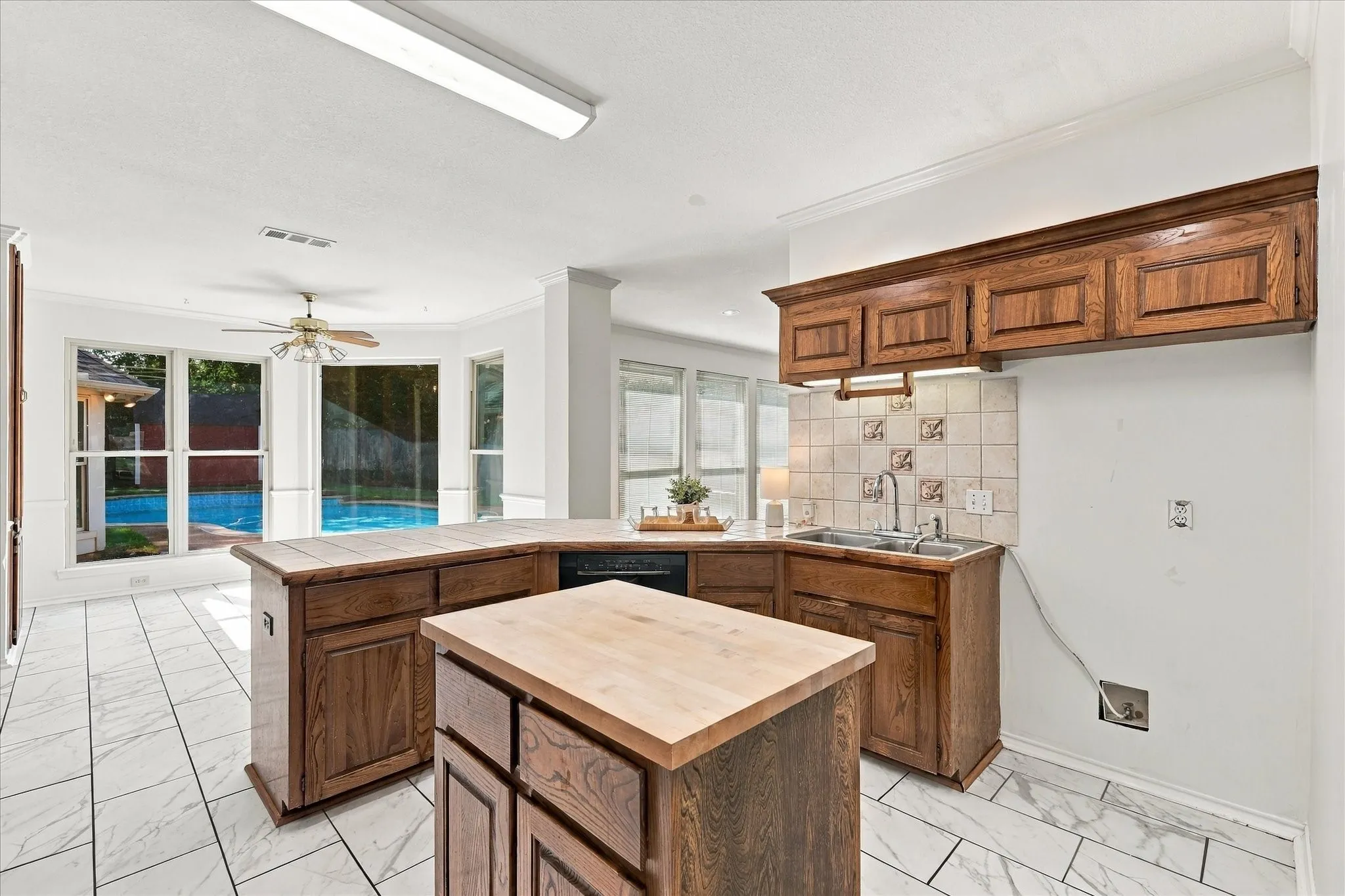 Kitchen featuring wood cabinetry, a center island with a wood countertop, and a tile backsplash