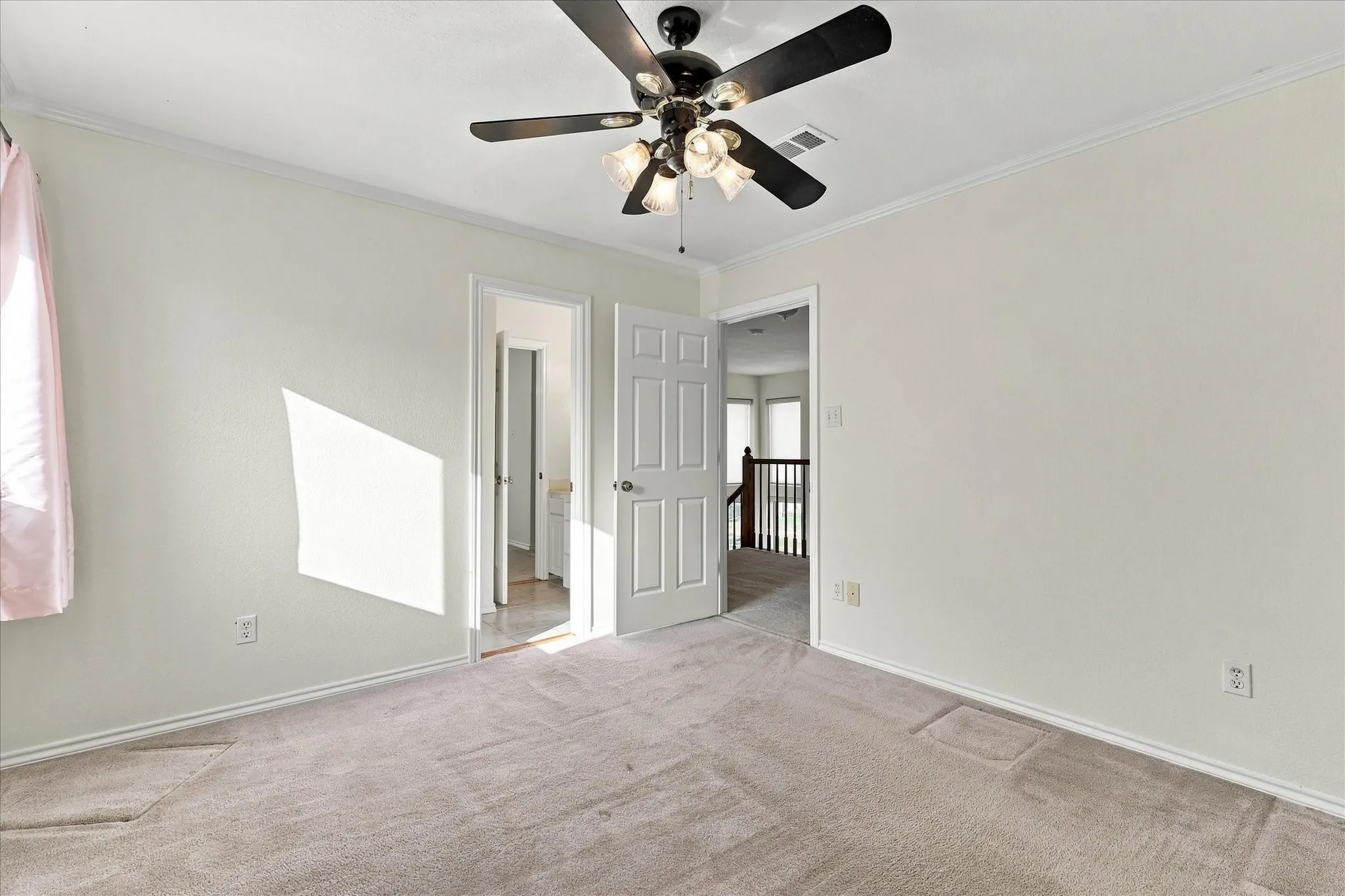 Looking out of bedroom with ensuite bath Neutral-toned walls, ceiling fan, and light-colored carpeting