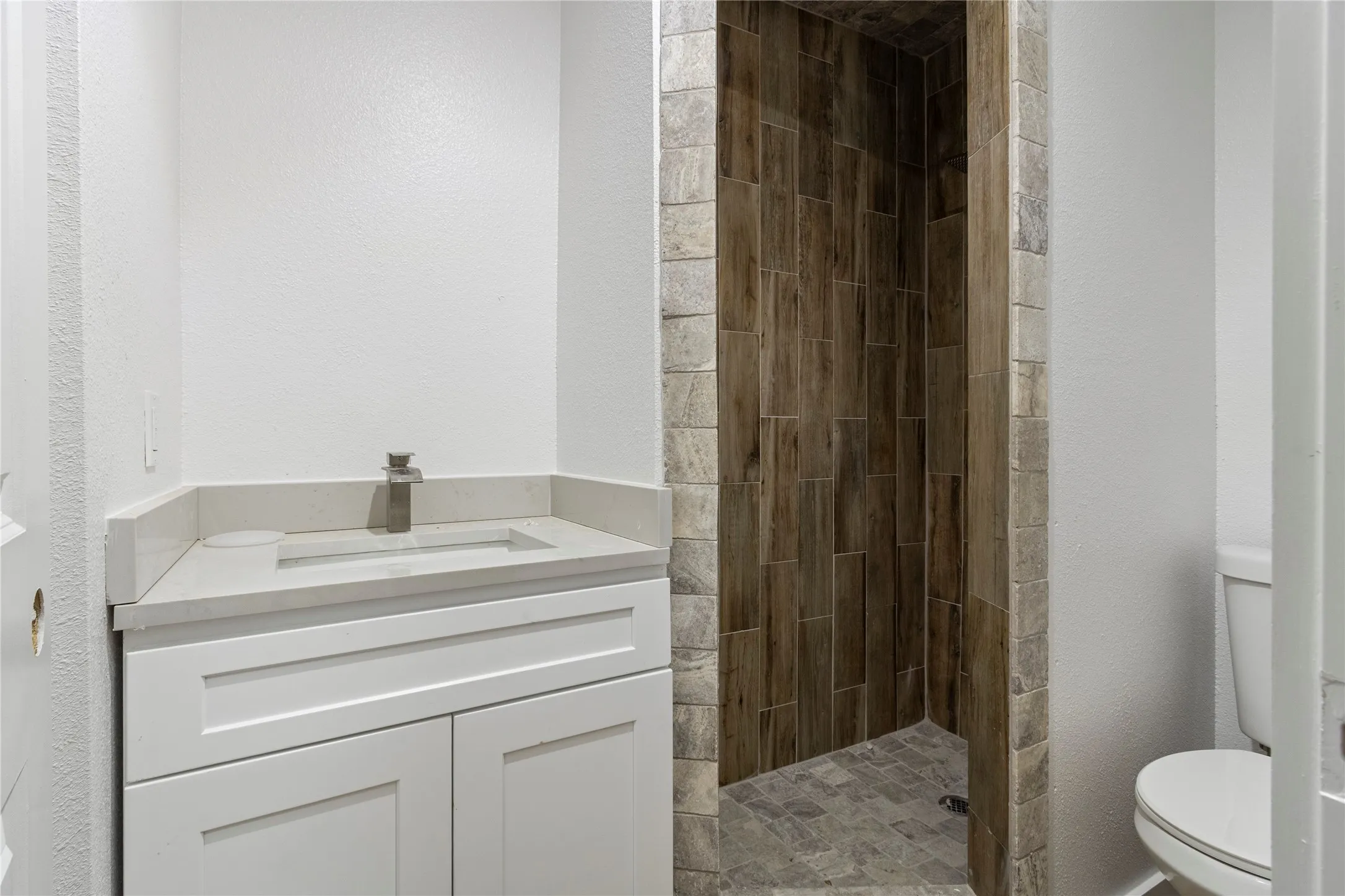 White vanity with a neutral countertop, undermount sink, and brushed nickel faucet