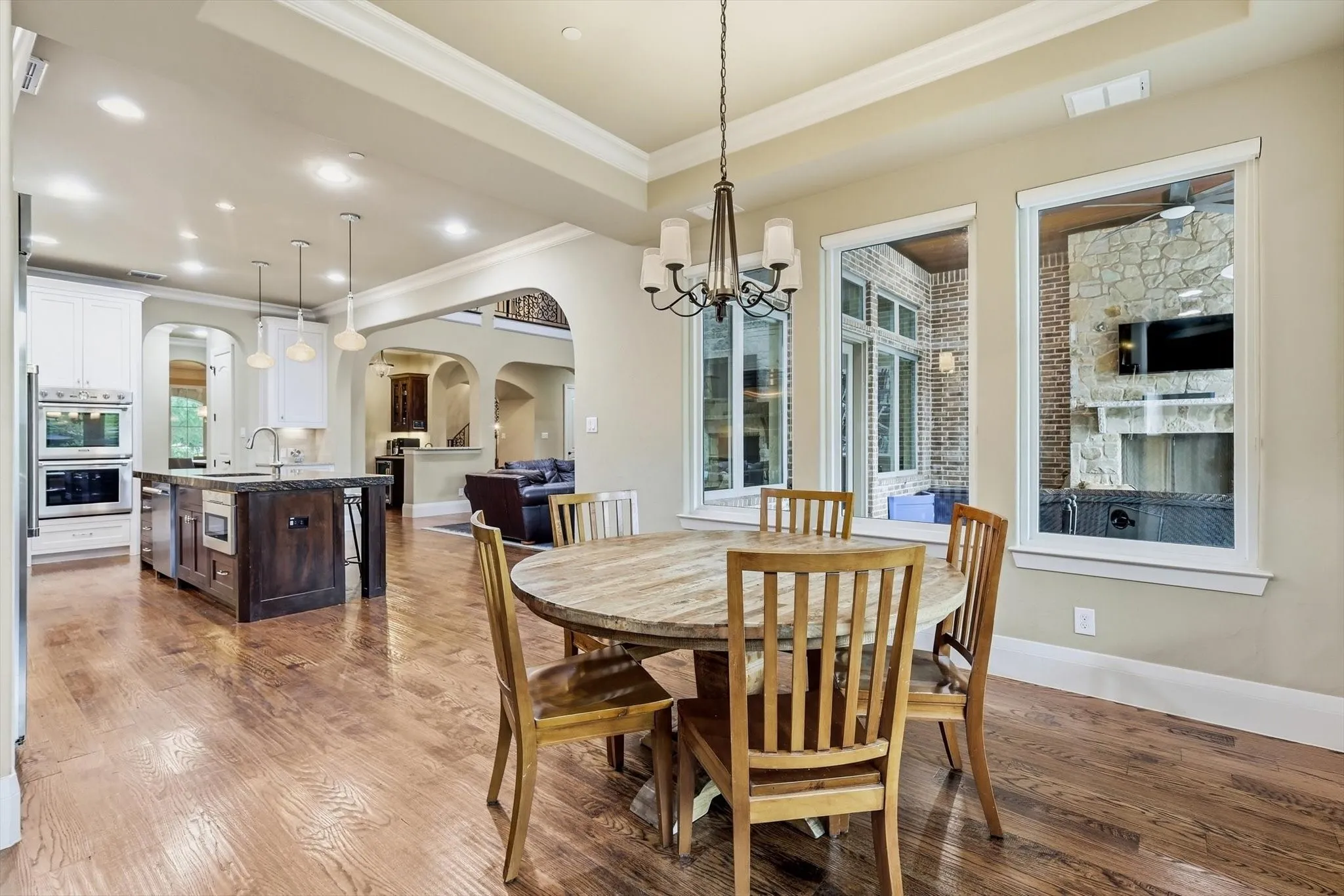 And from the spacious informal dining area, the open plan layout surrounded by windows and accesss to pool. Arched corridors and a glimpse of the outside fireplace.