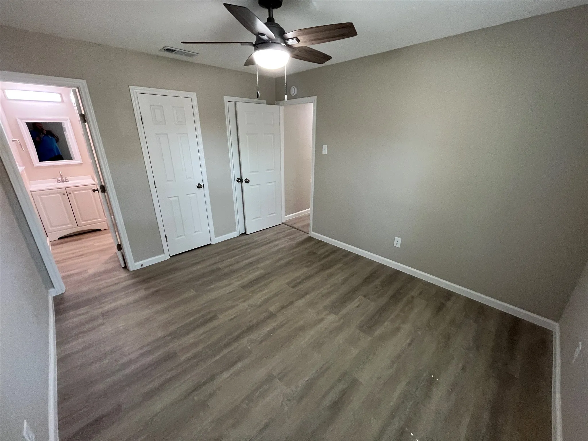 Wood-finish flooring throughout, neutral wall tones, and overhead ceiling fan with lighting