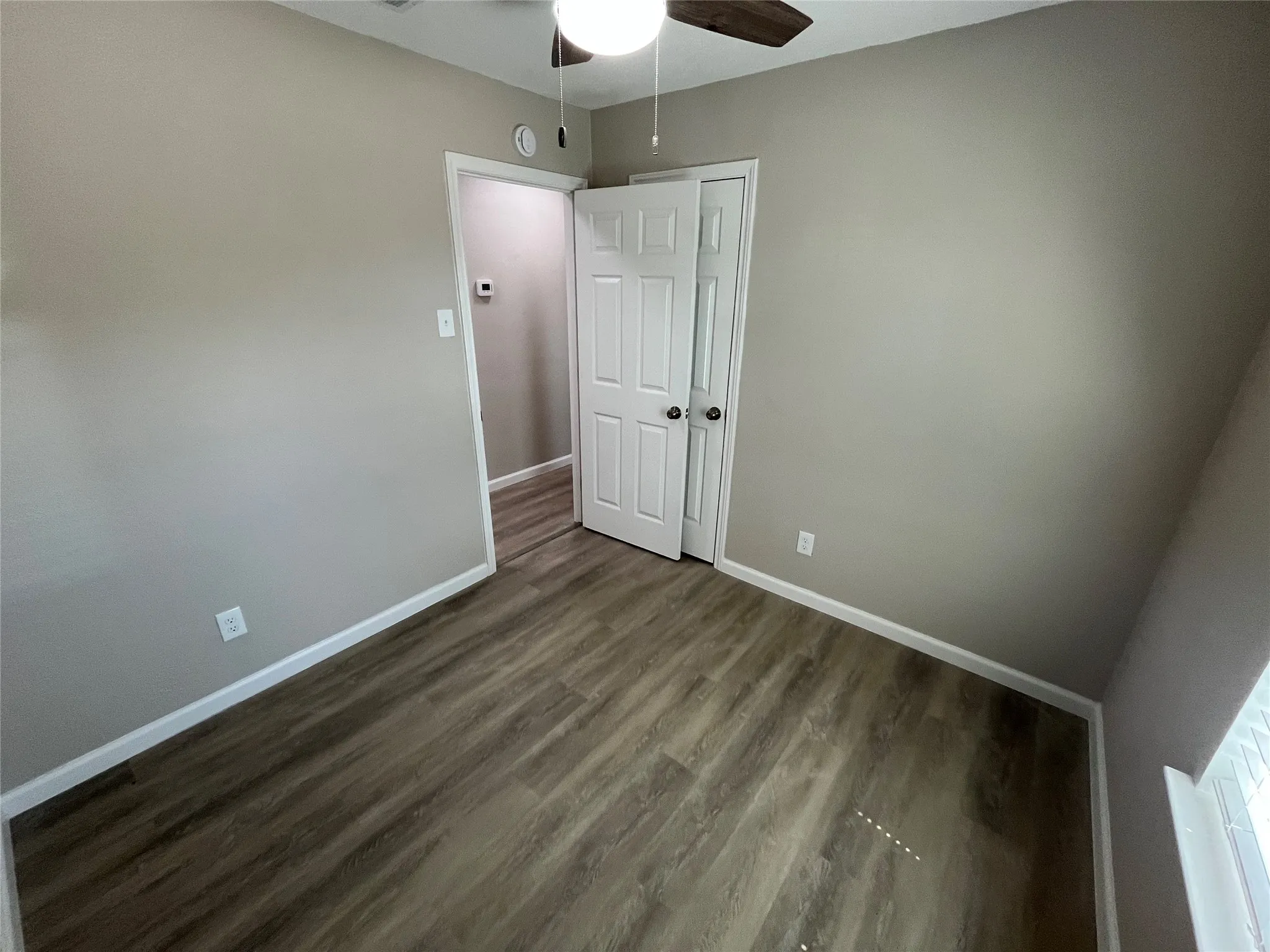 Wood-finish flooring throughout, neutral wall color, and white trim