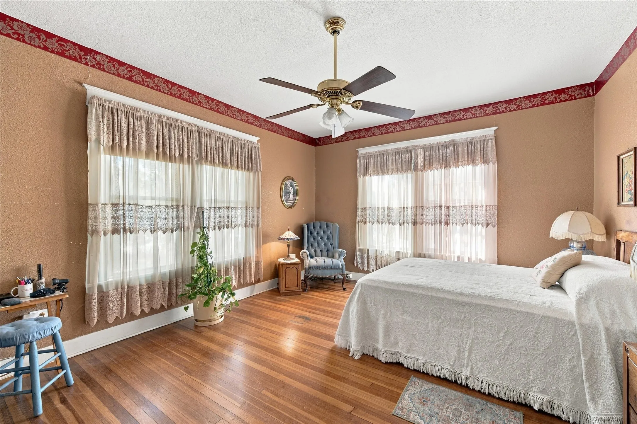 Hardwood flooring, two large windows, ceiling fan with integrated lighting, decorative wall trim