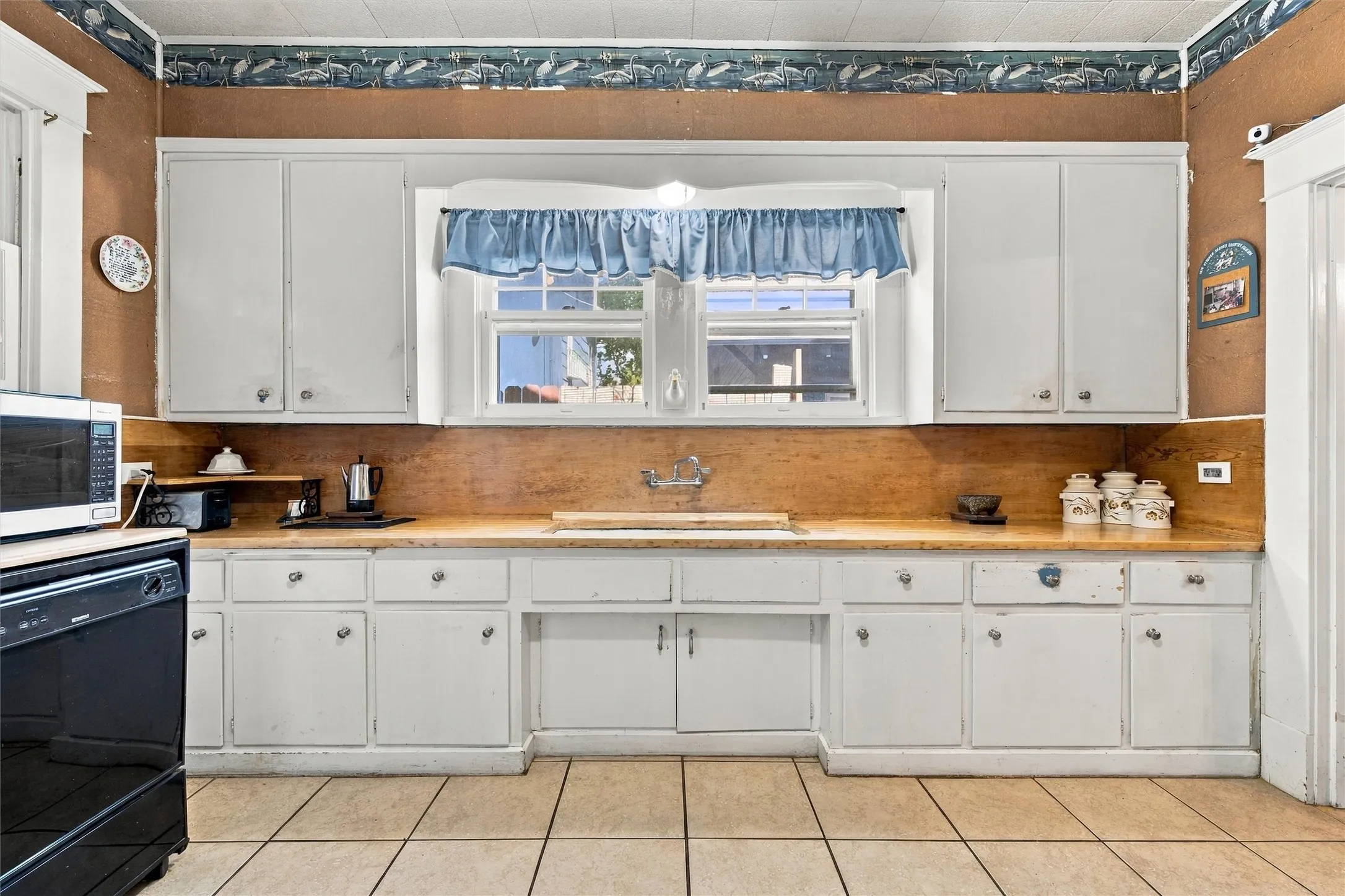 White cabinetry with ample storage, wood-finish countertops, and a double-basin sink