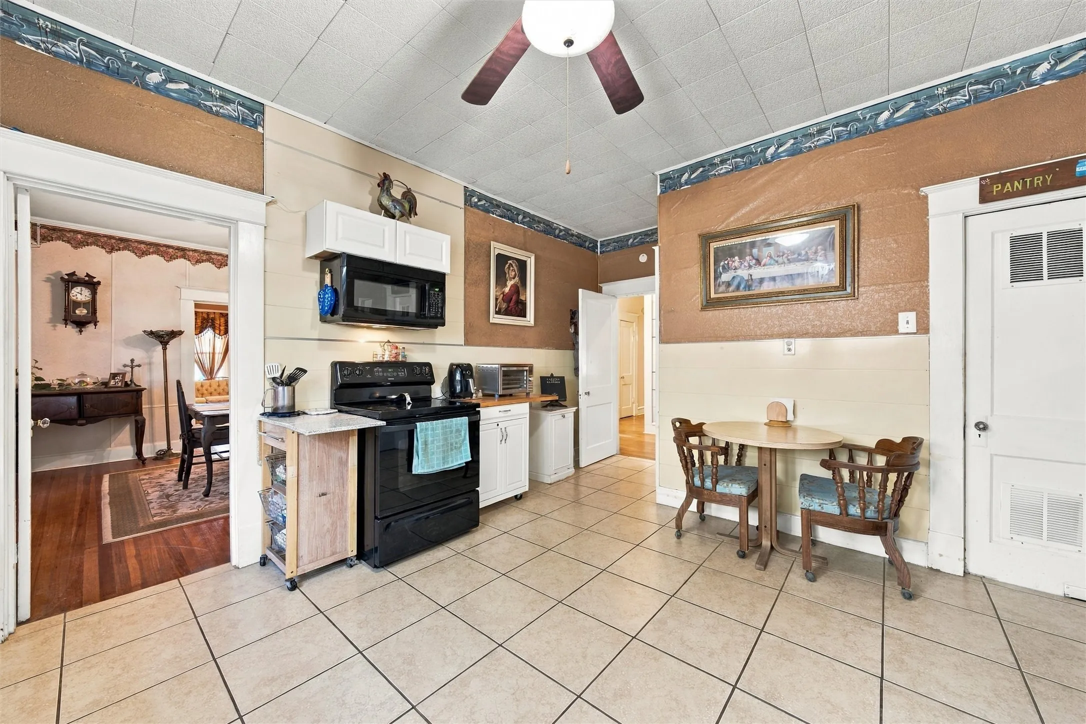 Tile flooring, a ceiling fan, and white upper cabinetry