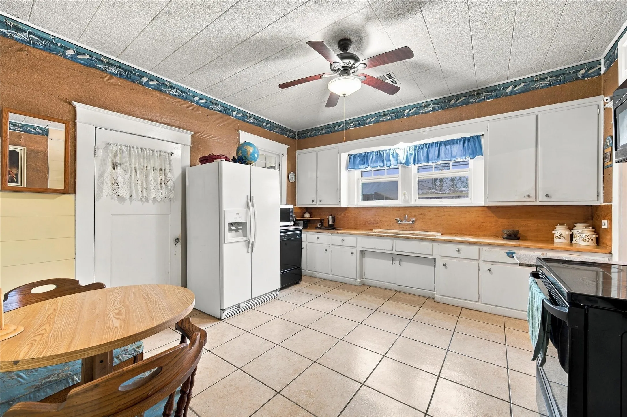 Kitchen featuring tile flooring, white cabinetry, a built-in ceiling fan, and wood-finish countertops