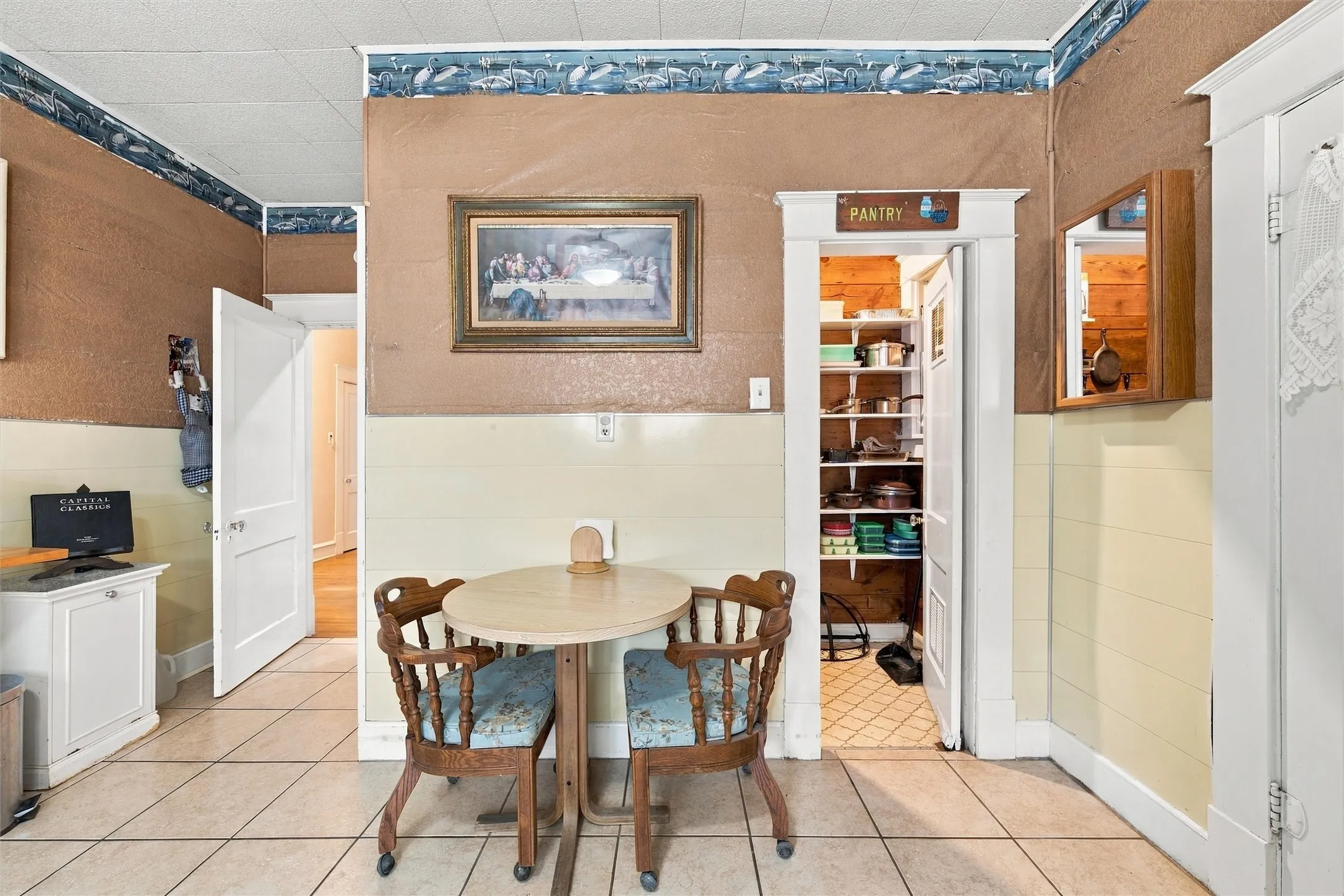 Tile flooring, built-in pantry with shelving, paneled wainscoting, and white trim throughout