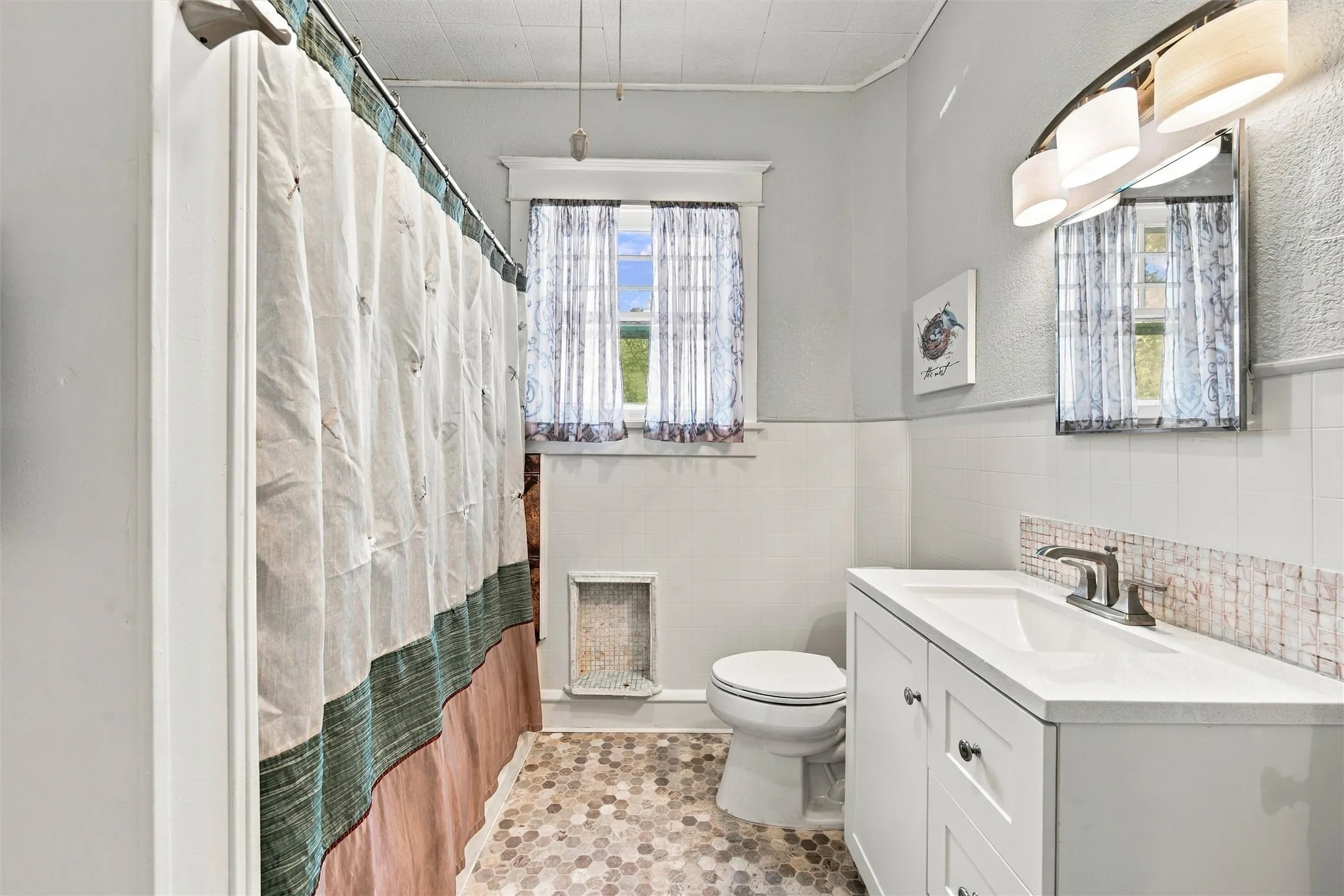 White vanity with integrated sink, mosaic tile backsplash, and hexagonal floor tiling