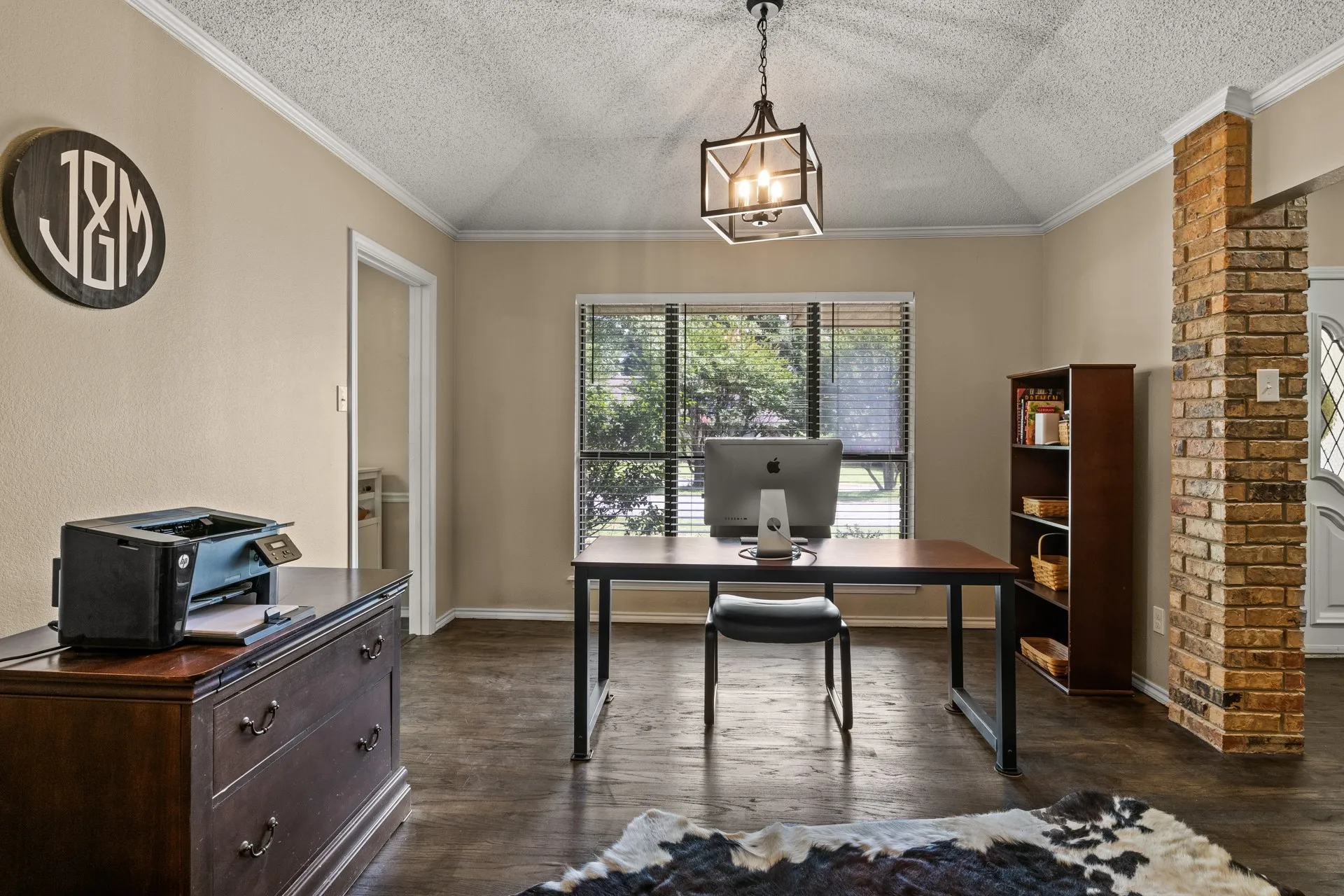 Home office featuring a textured ceiling, dark wood-style floors, crown molding, and ornate columns