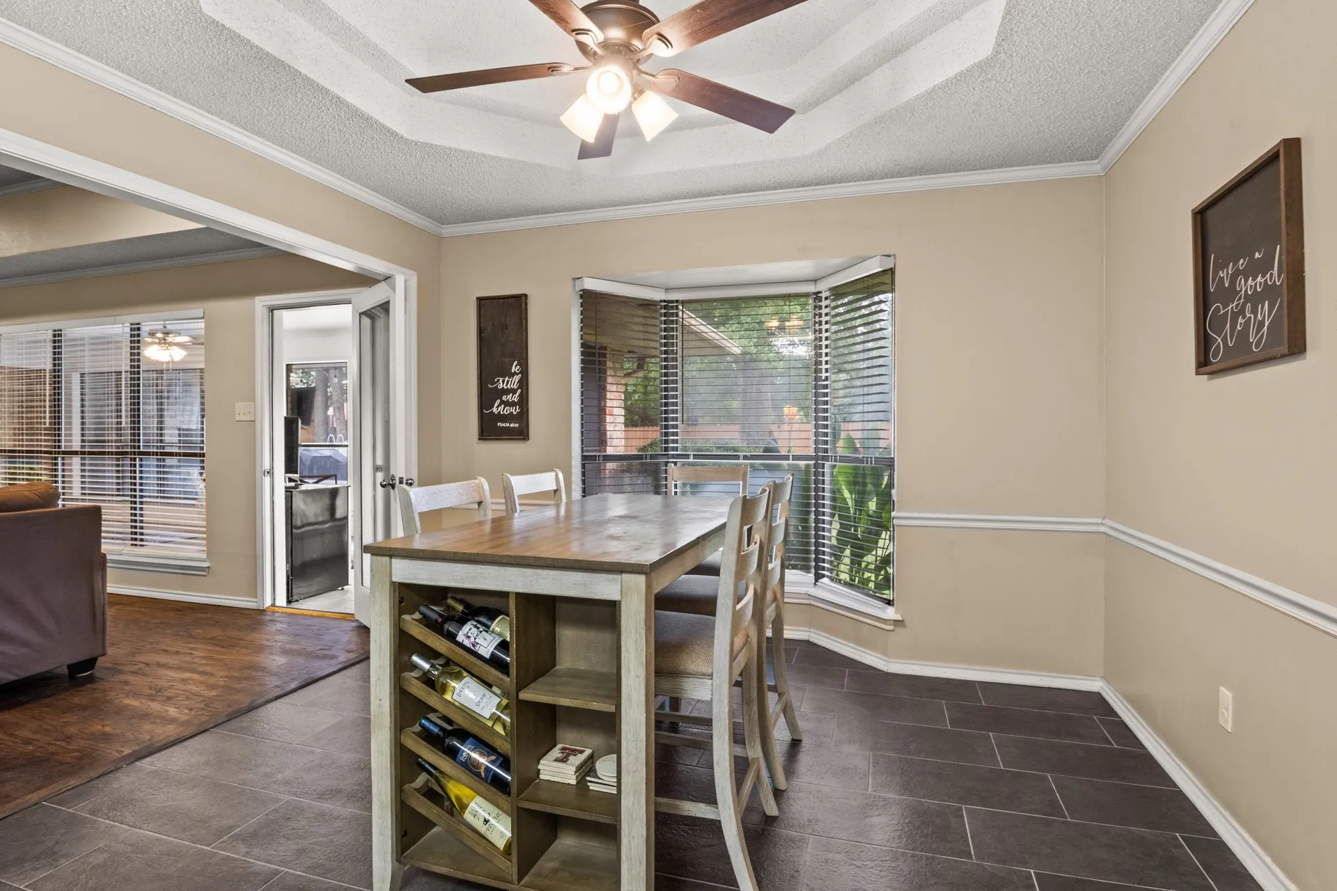 Tiled dining room with healthy amount of natural light, a ceiling fan, a textured ceiling, ornamental molding, and a raised ceiling