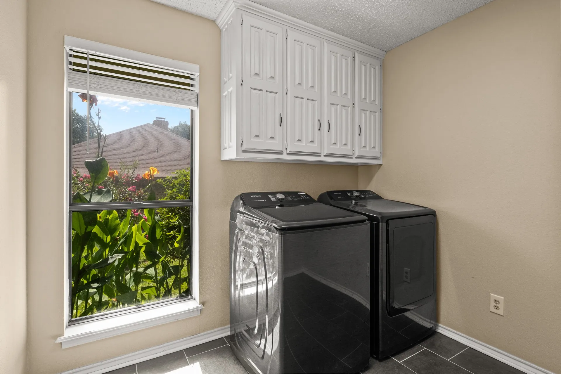 Laundry area featuring washer and dryer, cabinet space, dark tile patterned floors, and a textured ceiling