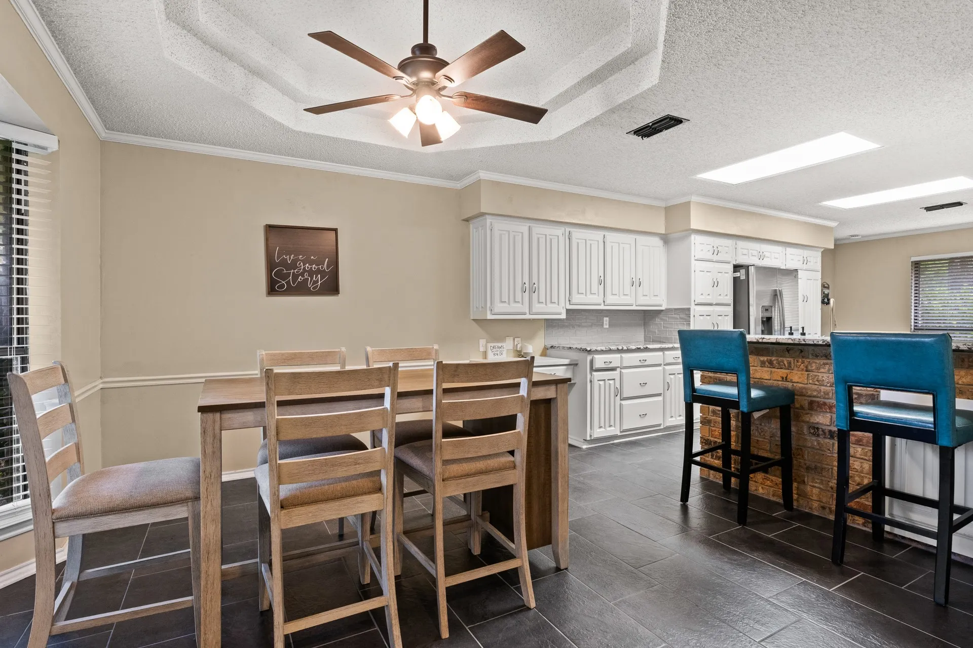 Dining area with a textured ceiling, ceiling fan, ornamental molding, and dark tile patterned floors
