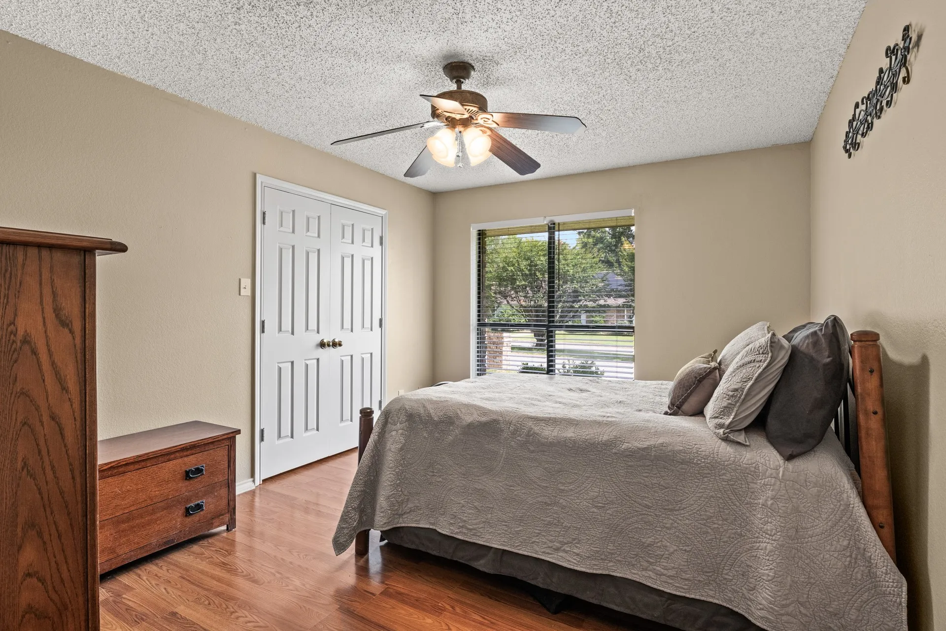 Bedroom with wood finished floors, a textured ceiling, ceiling fan, and a closet