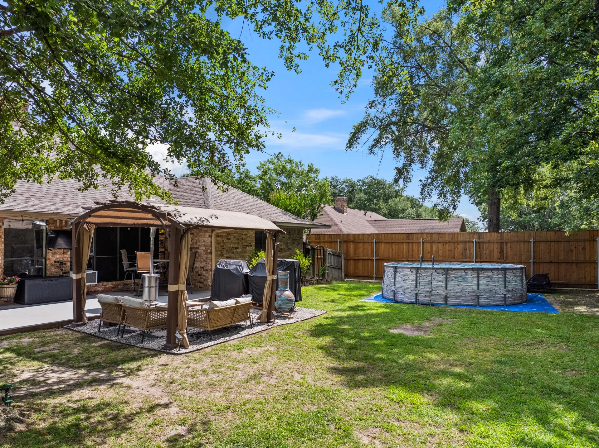 Fenced backyard featuring a gazebo and an outdoor living space