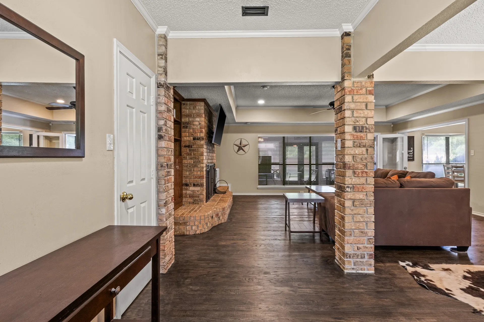Living room with wood finished floors, a fireplace, decorative columns, plenty of natural light, and crown molding