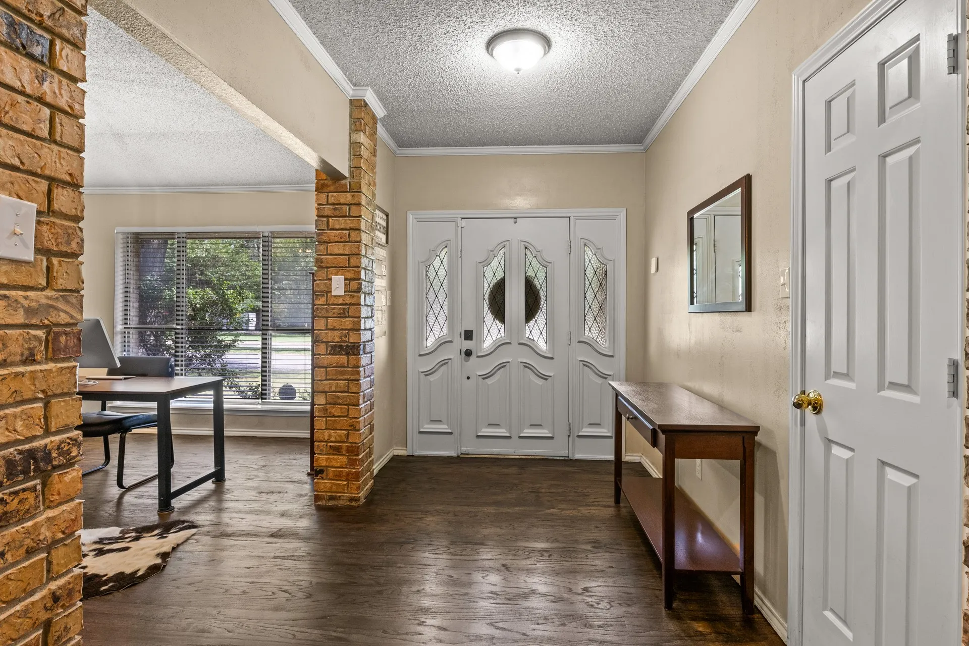 Foyer with a textured ceiling, dark wood-style floors, and ornamental molding