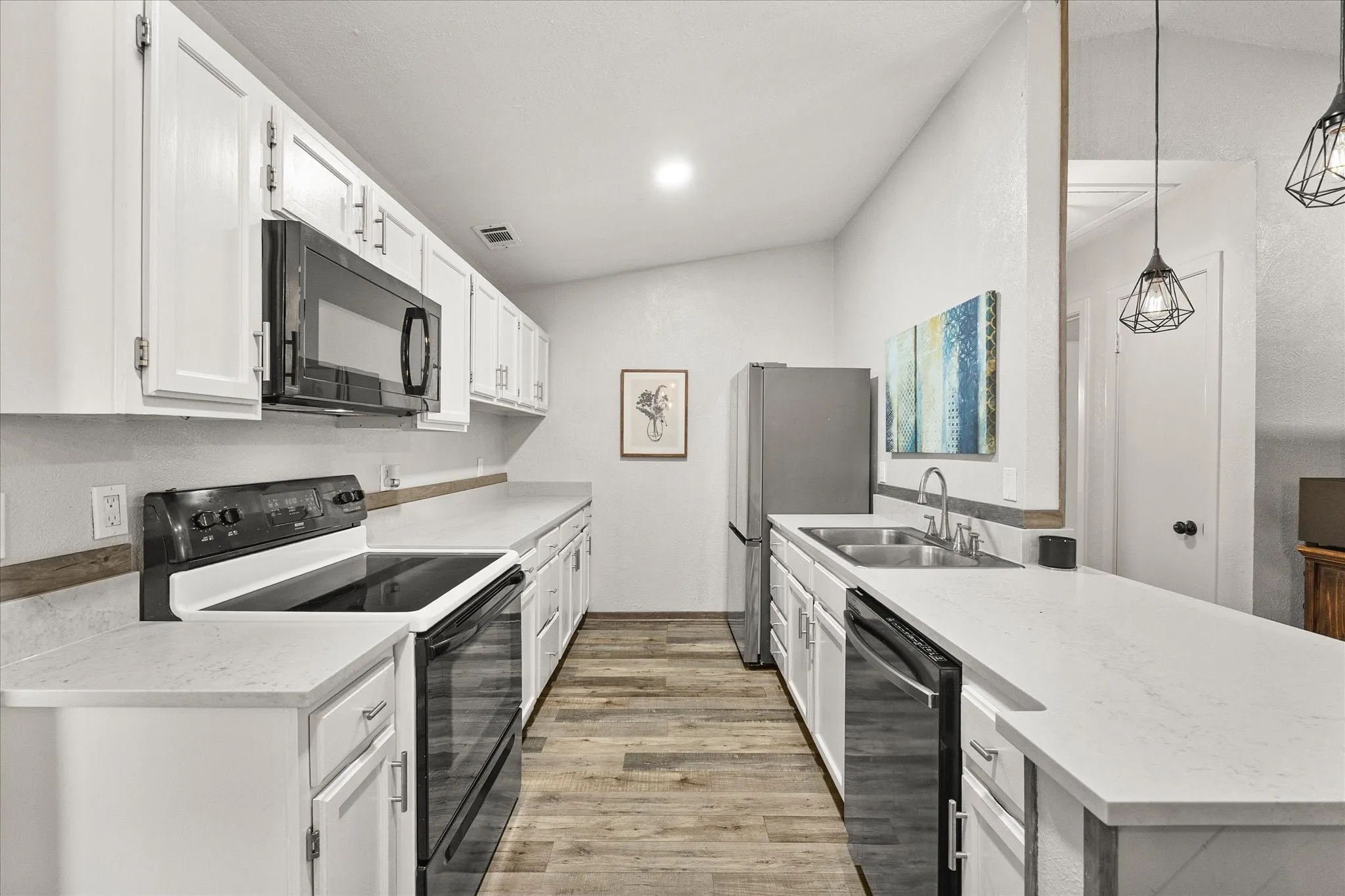 Galley kitchen featuring white cabinetry, light countertops, and stainless steel appliances