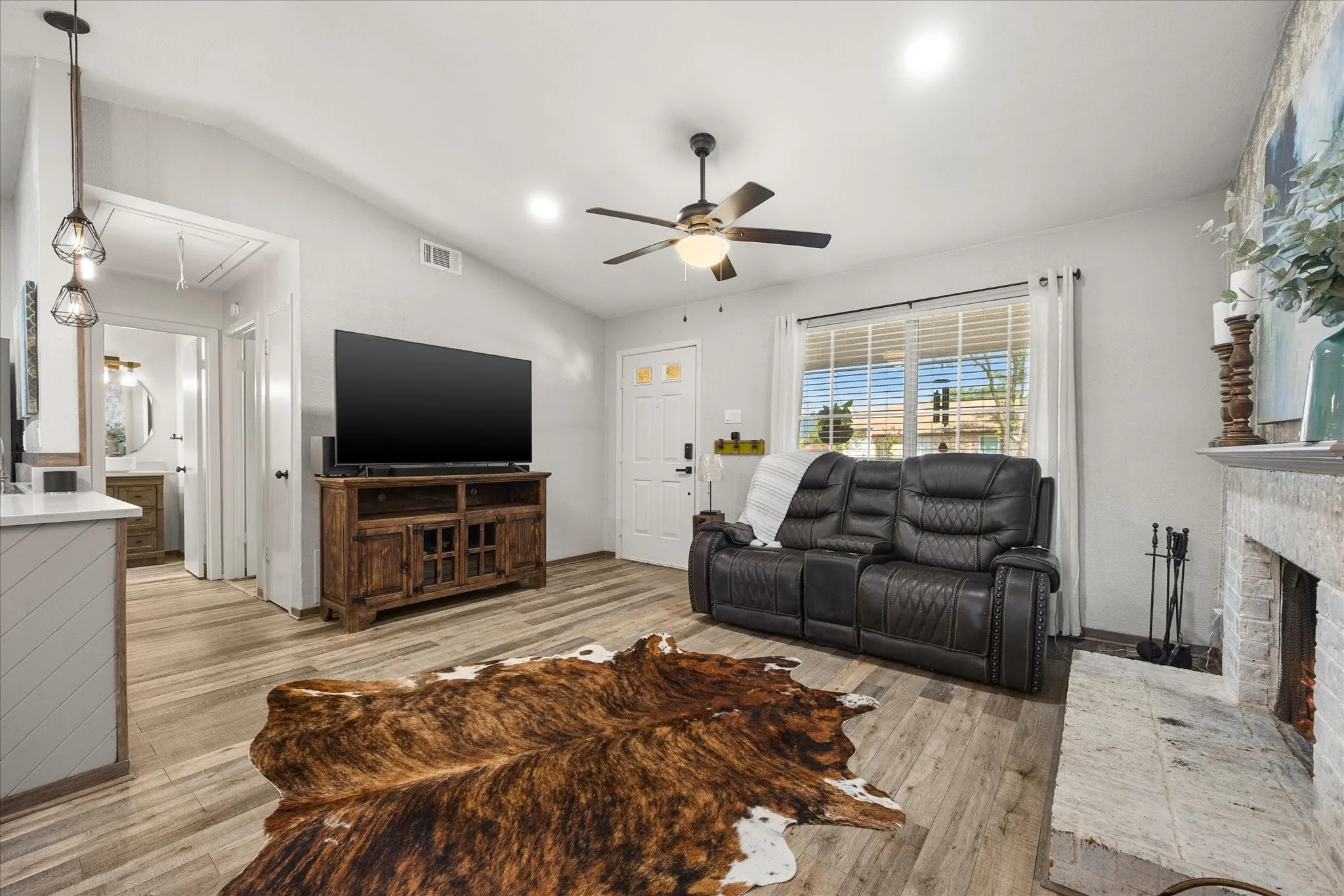 Ceiling fan, fireplace with stone surround, and recessed lighting