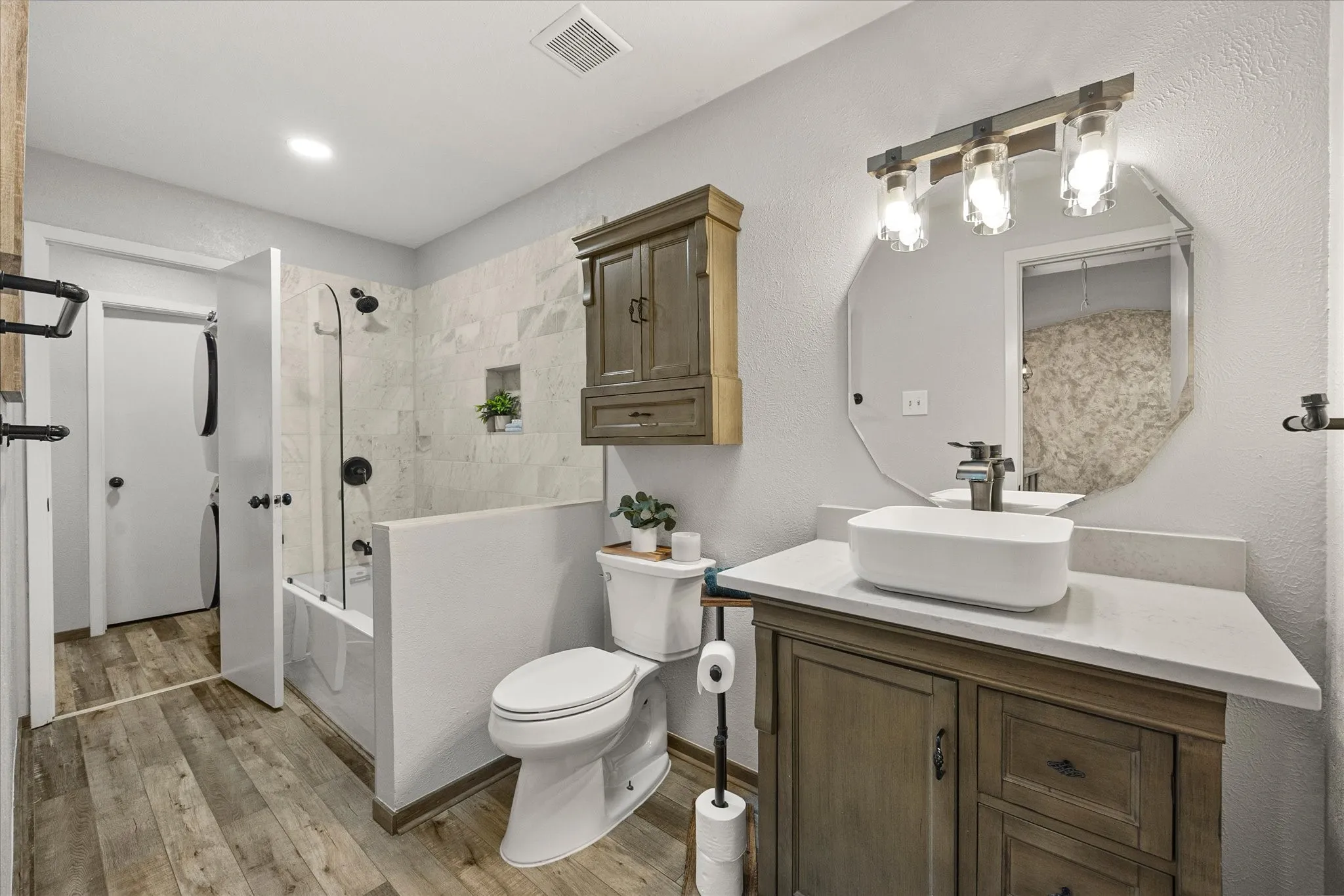 Wood-finish vinyl plank flooring with a white and with a dark wood-finish vanity featuring a rectangular vessel sink, complete with a dark wood-finish medicine cabinet