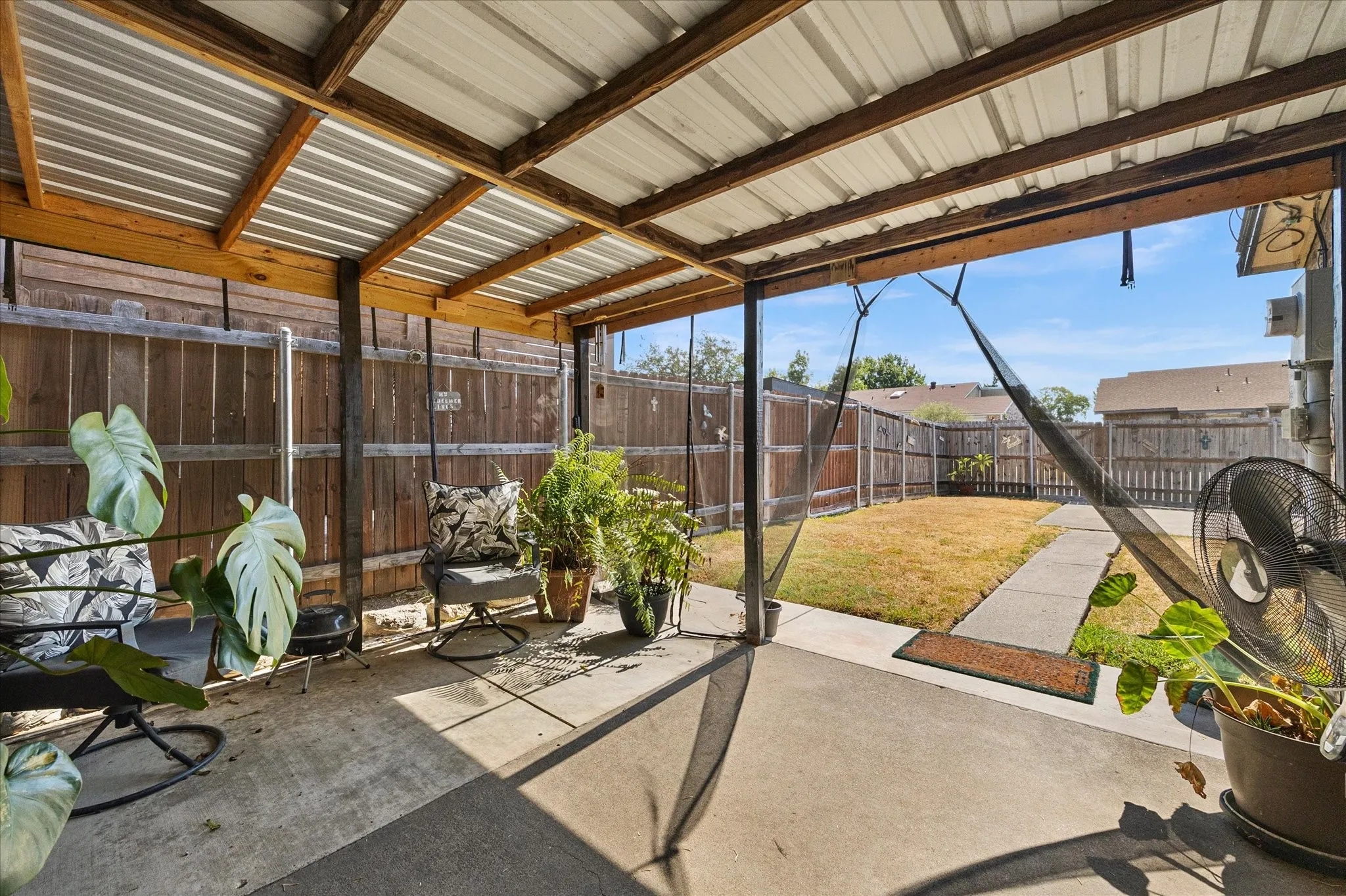Covered outdoor back patio with a corrugated metal roof and exposed wood beams