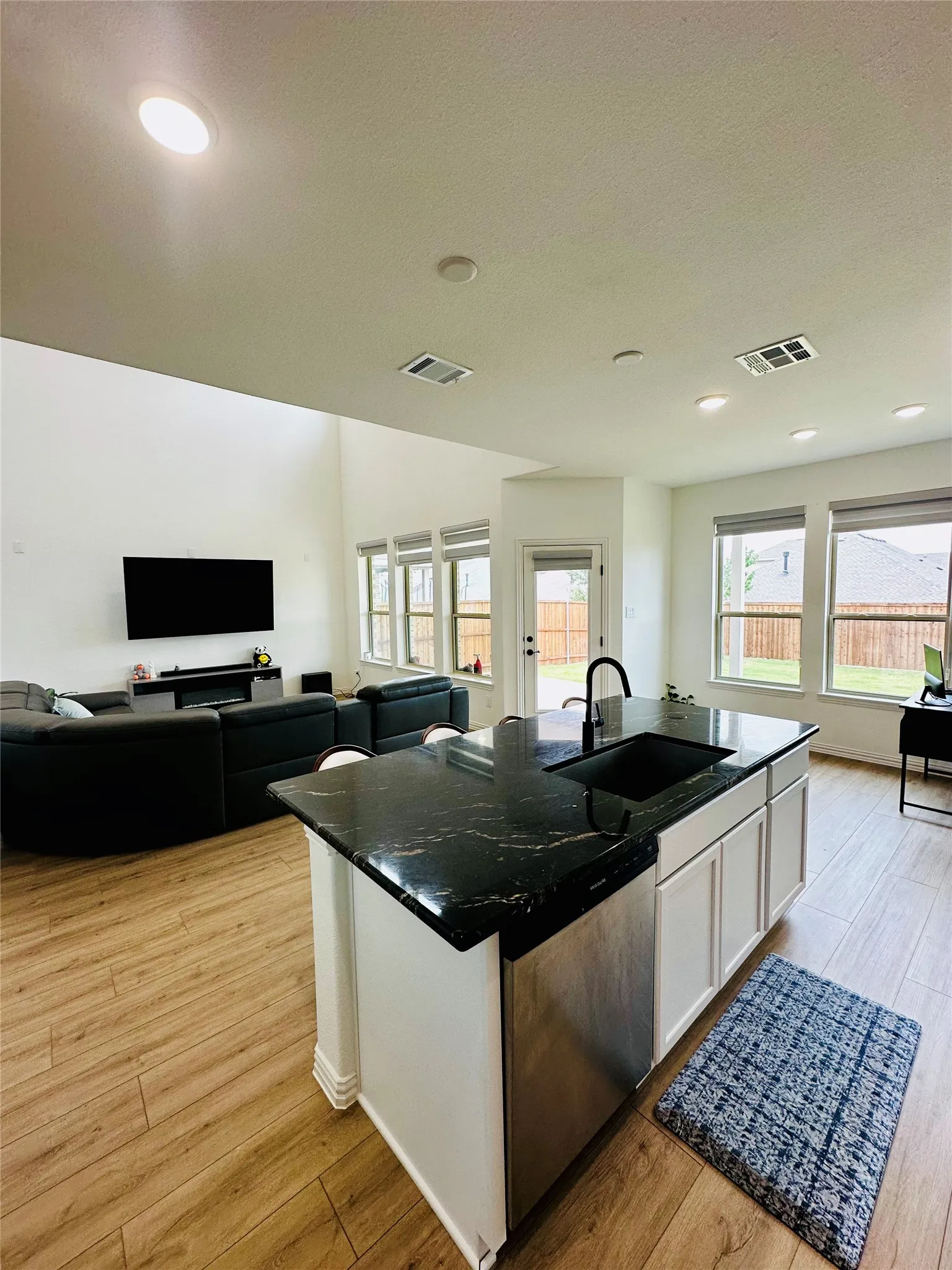 Spacious open-concept layout with wood-finish flooring, recessed lighting, and ample natural light through multiple windows