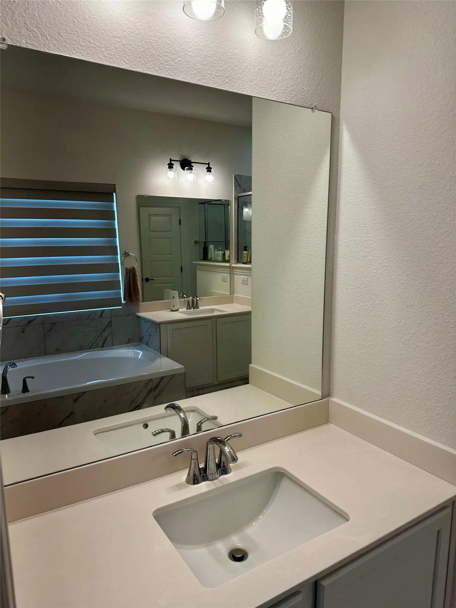 Dual sink vanity with an undermount sink, chrome faucet, and expansive wall mirror