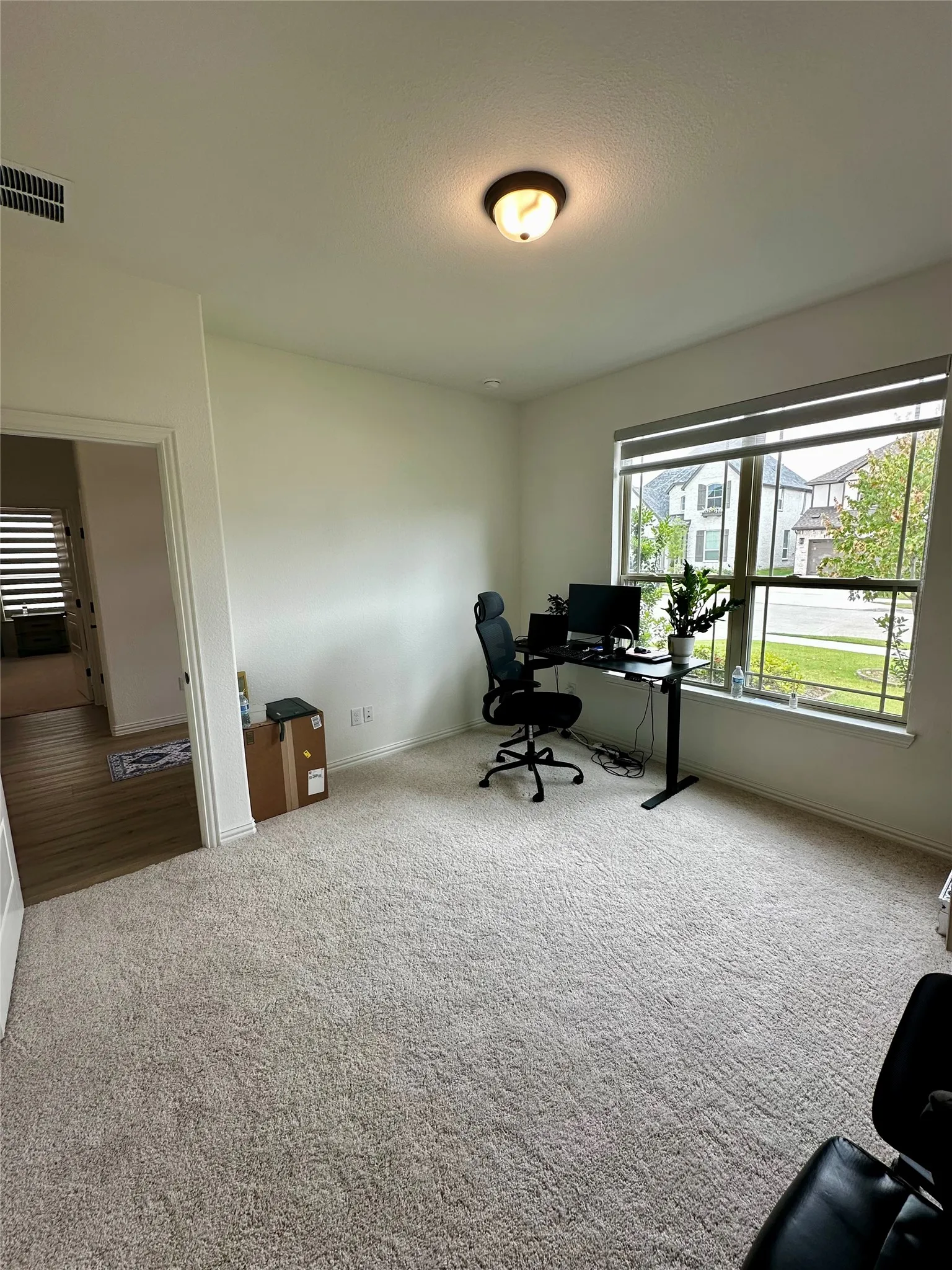 Plush carpeting, recessed lighting, and a large window with privacy blinds