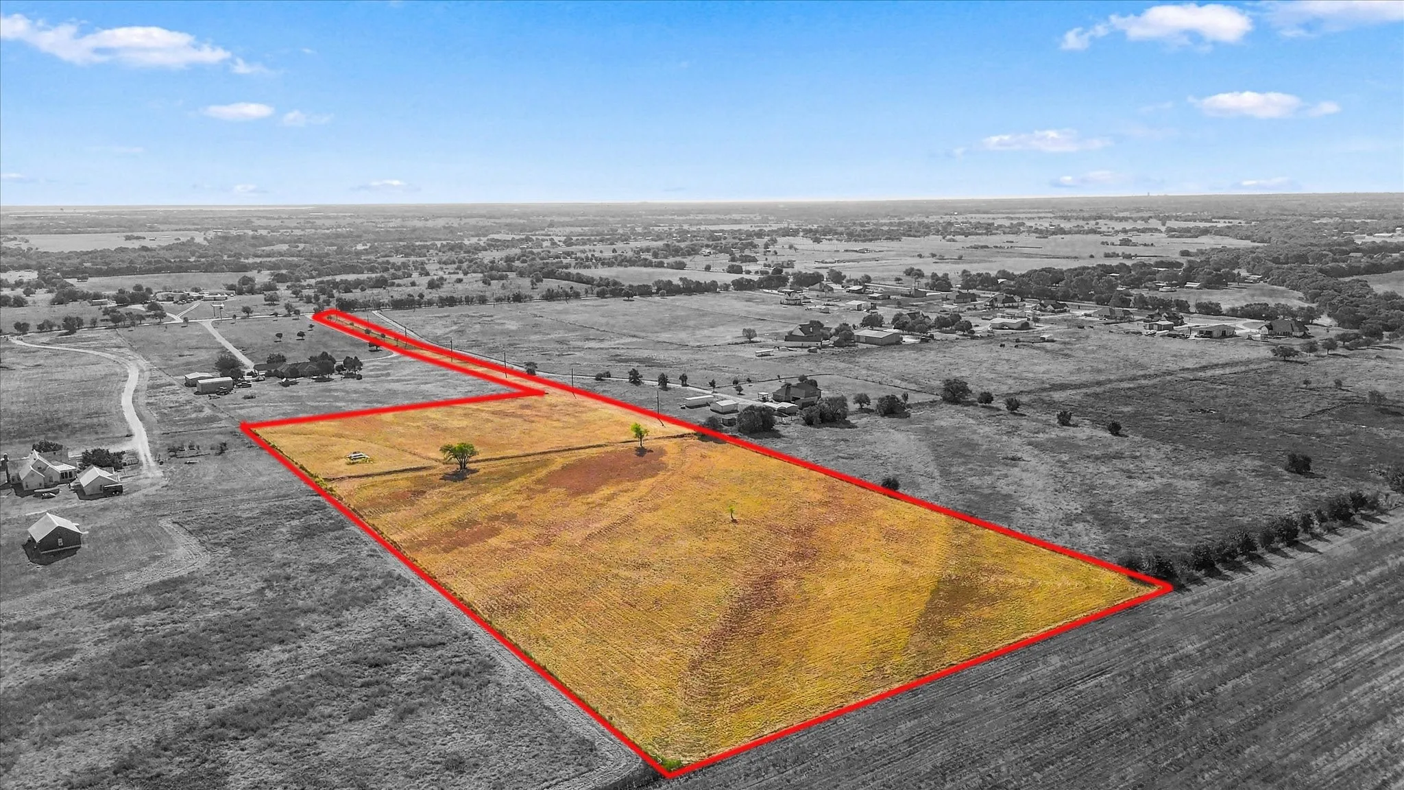 Expansive open land with a clear boundary marking, featuring scattered trees and a natural landscape