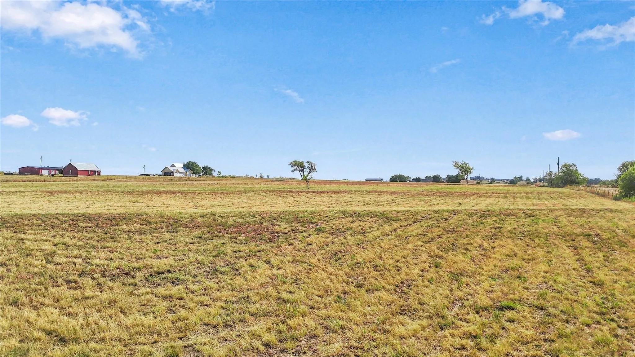 Expansive open field with distant structures under a clear sky