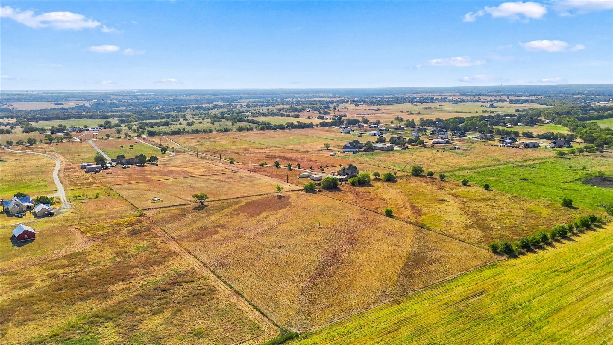 Expansive acreage with defined property lines, scattered mature trees, and agricultural fields