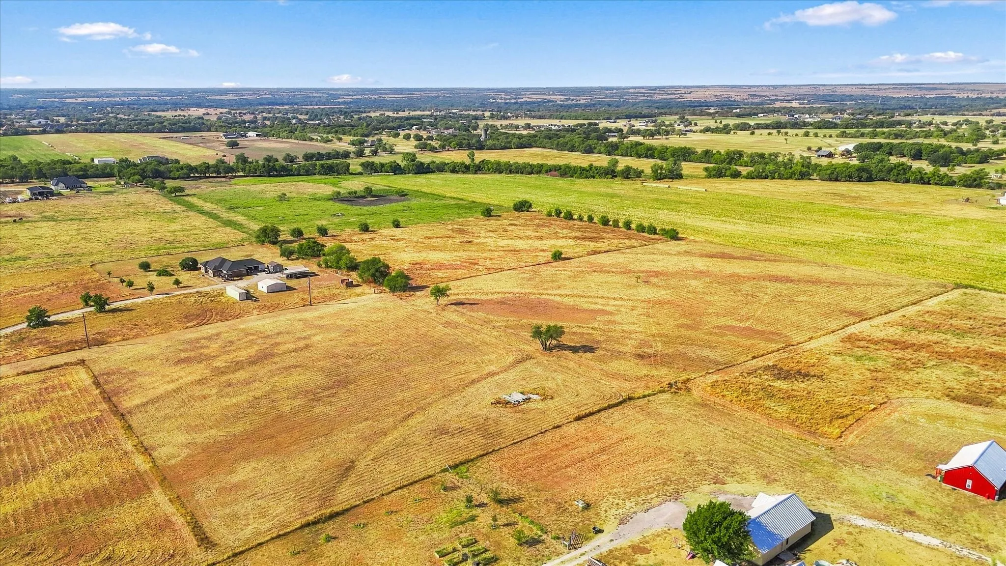 Expansive open fields with scattered trees and multiple structures