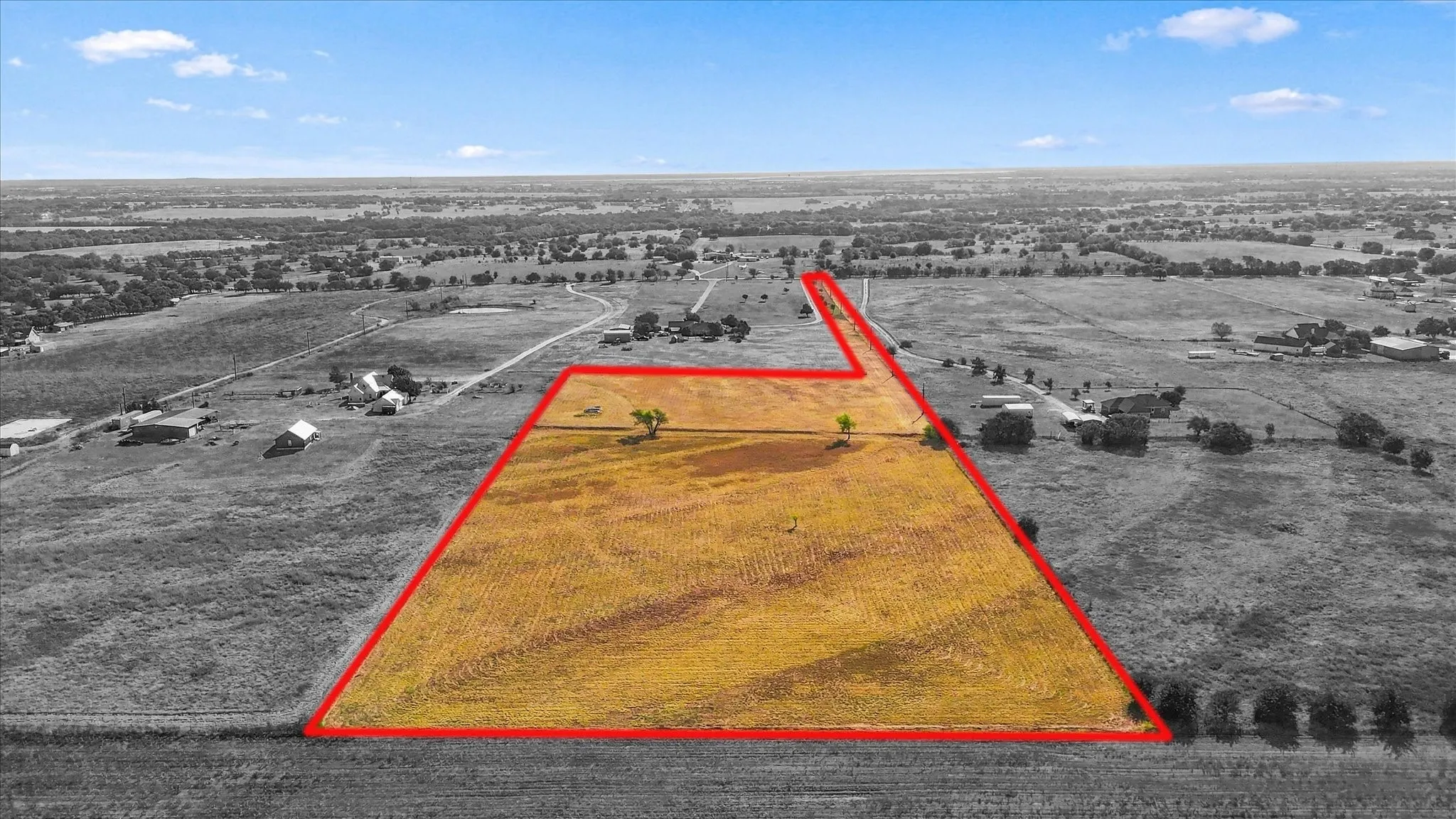 Expansive undeveloped land featuring a distinct boundary, open fields, and distant treelines