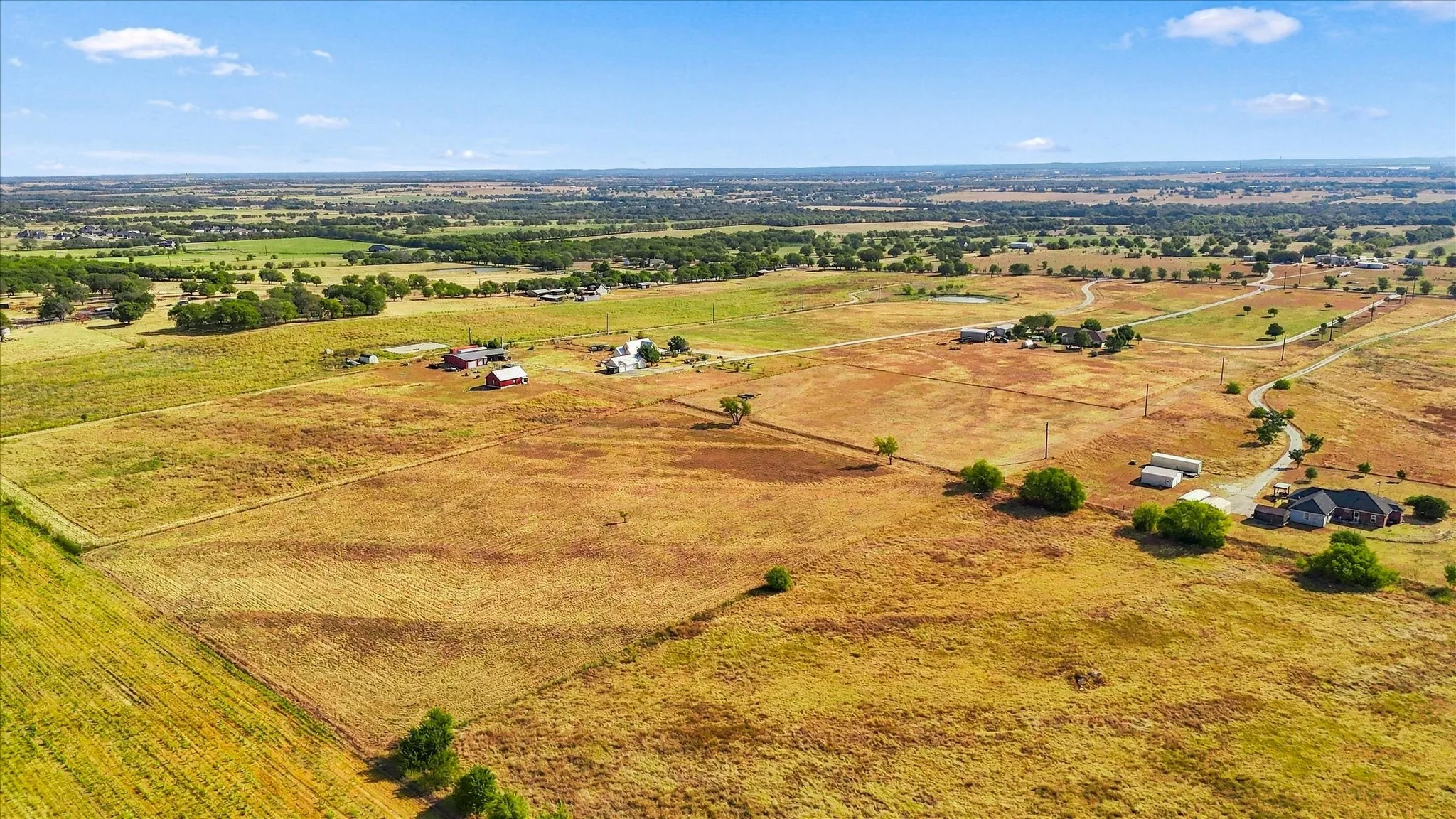 Expansive property featuring varied terrain, a winding private driveway, and multiple outbuildings