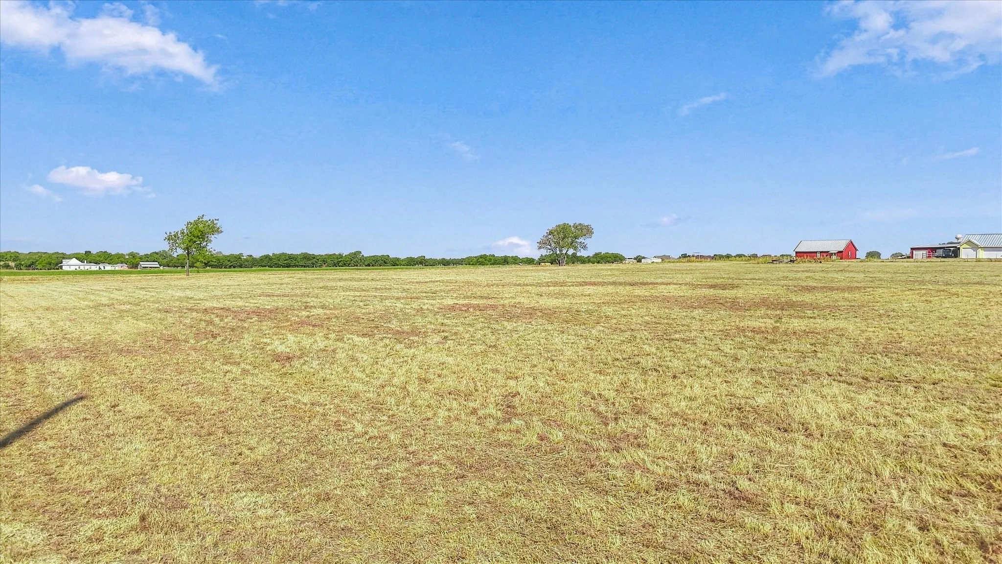 Expansive open field with distant structures under a clear sky