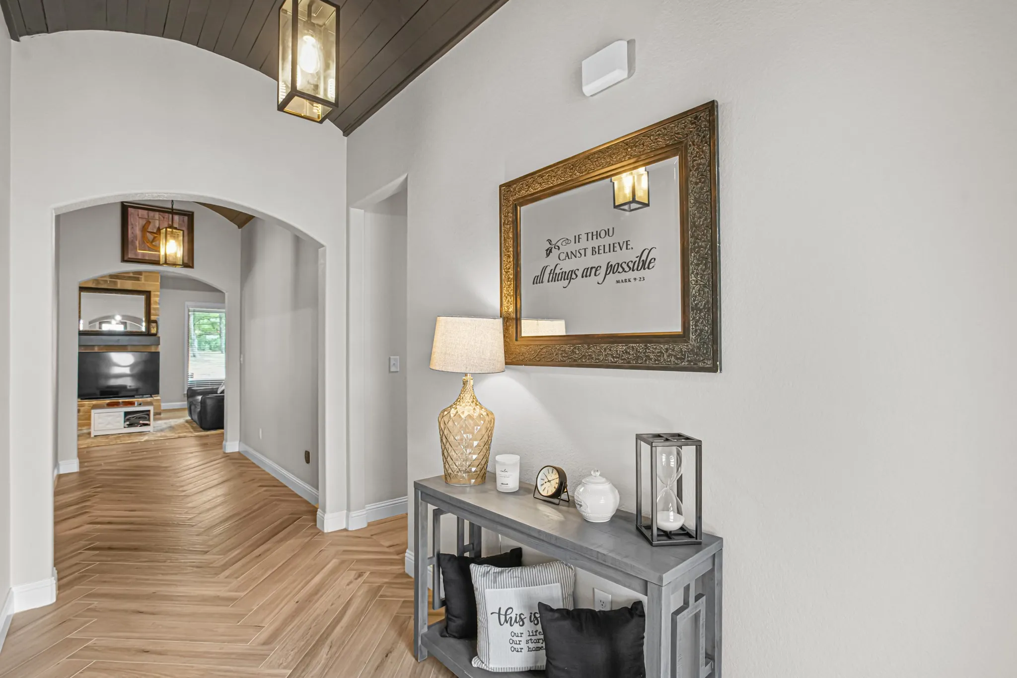 Herringbone wood-finish flooring, arched doorways, barrel-vaulted ceiling with wood paneling, and pendant lighting
