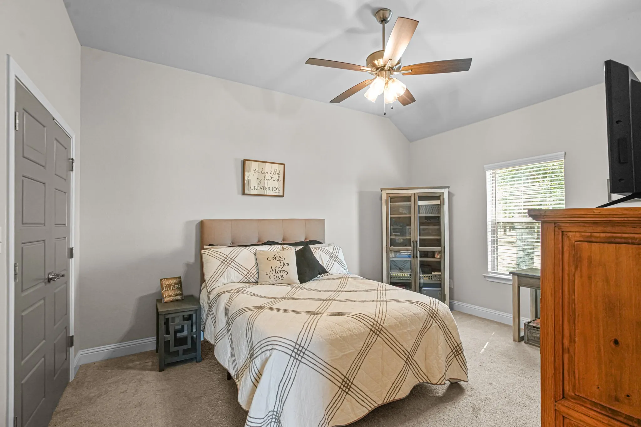 Vaulted ceiling, ceiling fan, carpet flooring, window with blinds, panel door