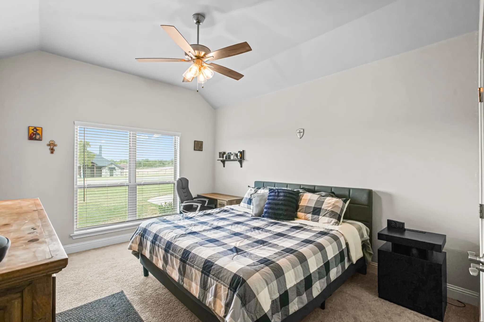 Vaulted ceiling featuring a ceiling fan with integrated lighting, large window with blinds, and neutral carpet flooring