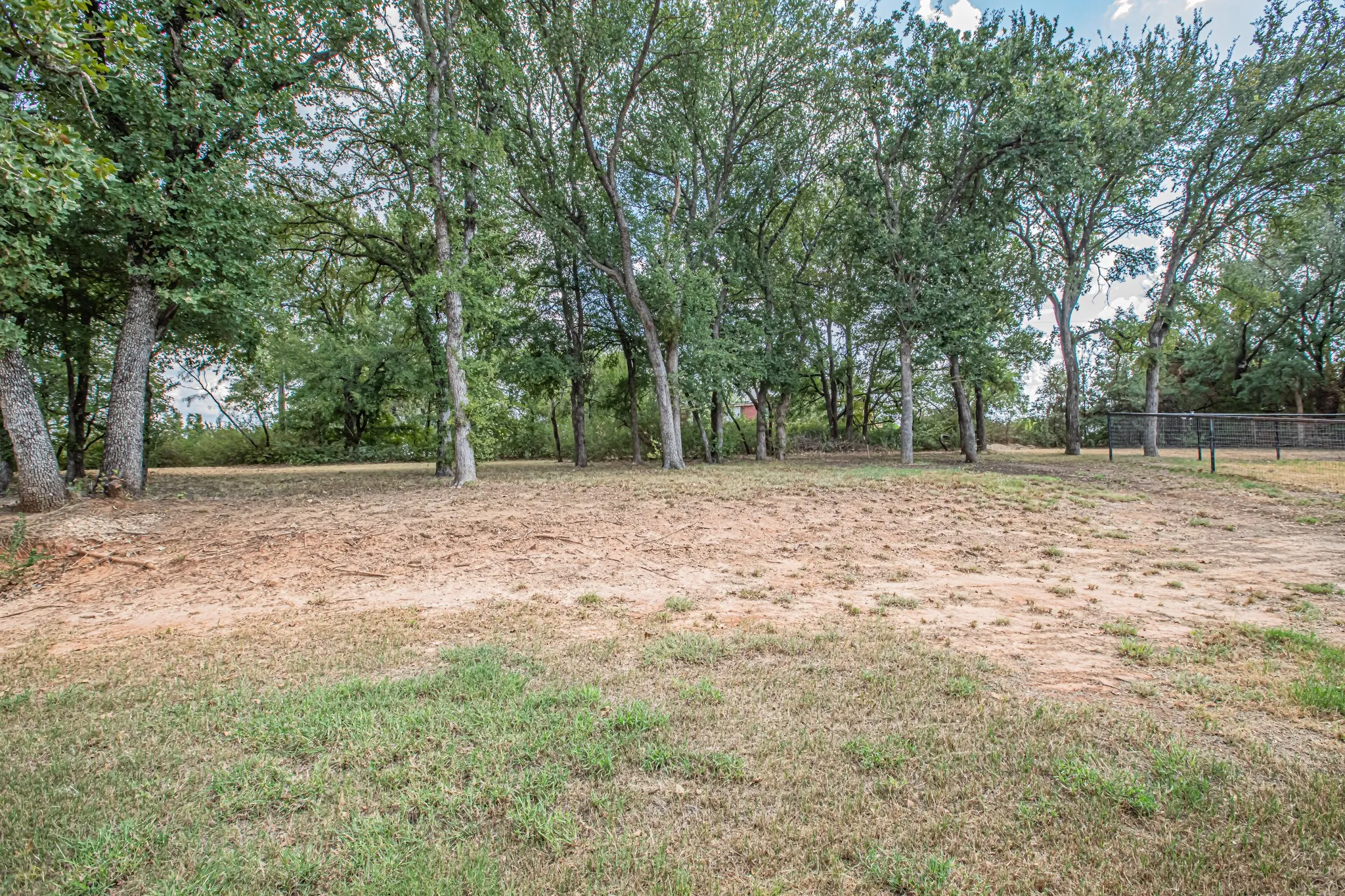 Expansive lot featuring mature trees and a partial perimeter fence
