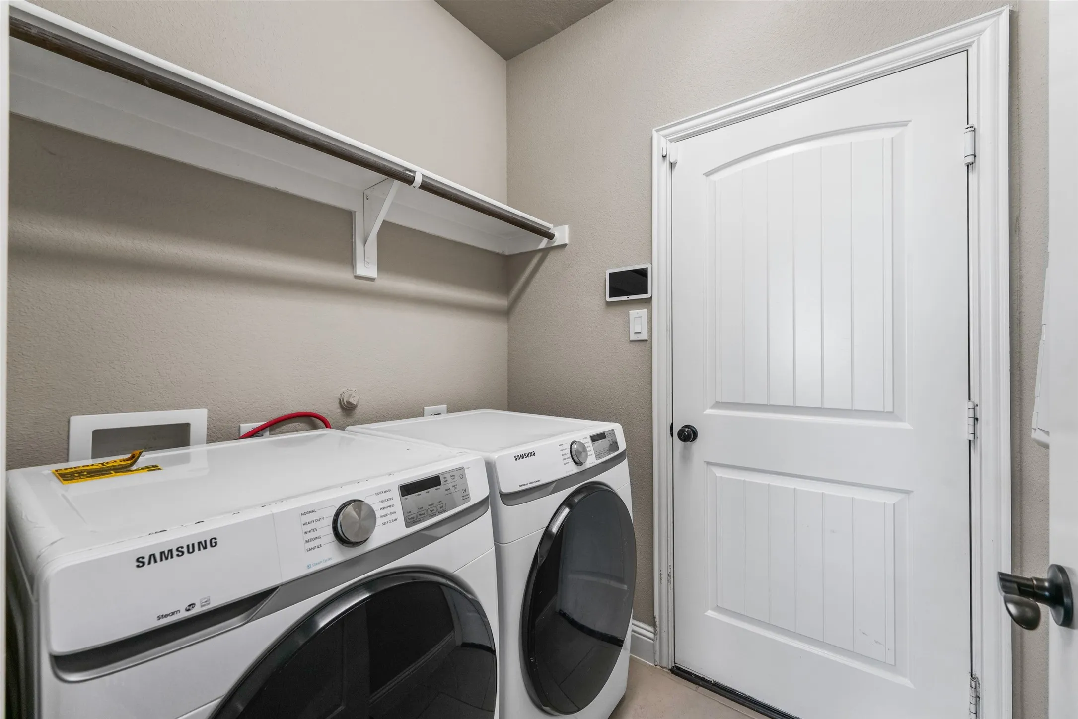 Laundry area featuring a wall-mounted shelf, hanging rod, and paneled door